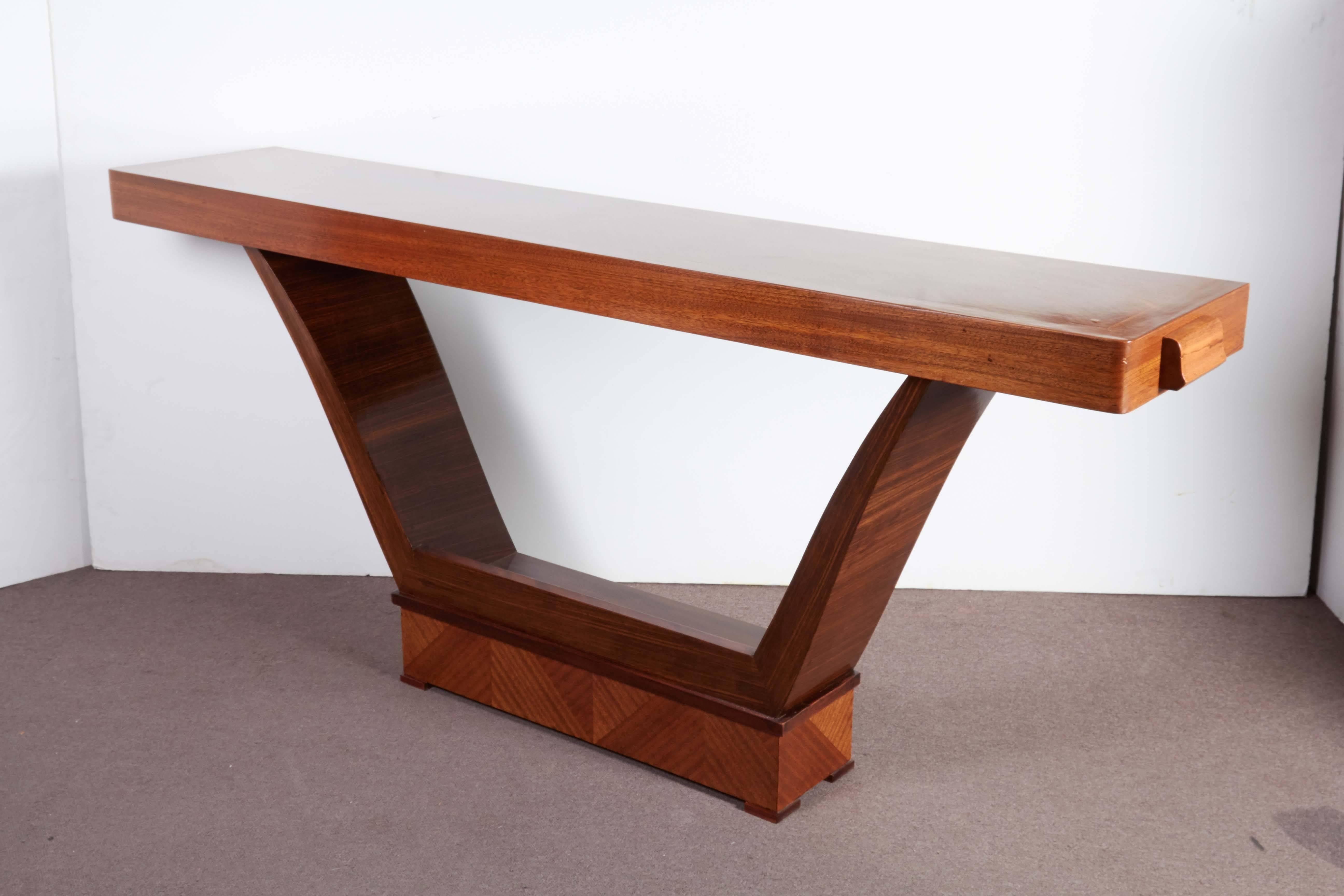 An elegant French moderne parquetry inlaid mahogany console of cubist design. Paquebot style in a semi-gloss satin lacquer finish with tapered, angular U-shaped palisander legs resting on a rectangular plinth with parquetry details. The top matches