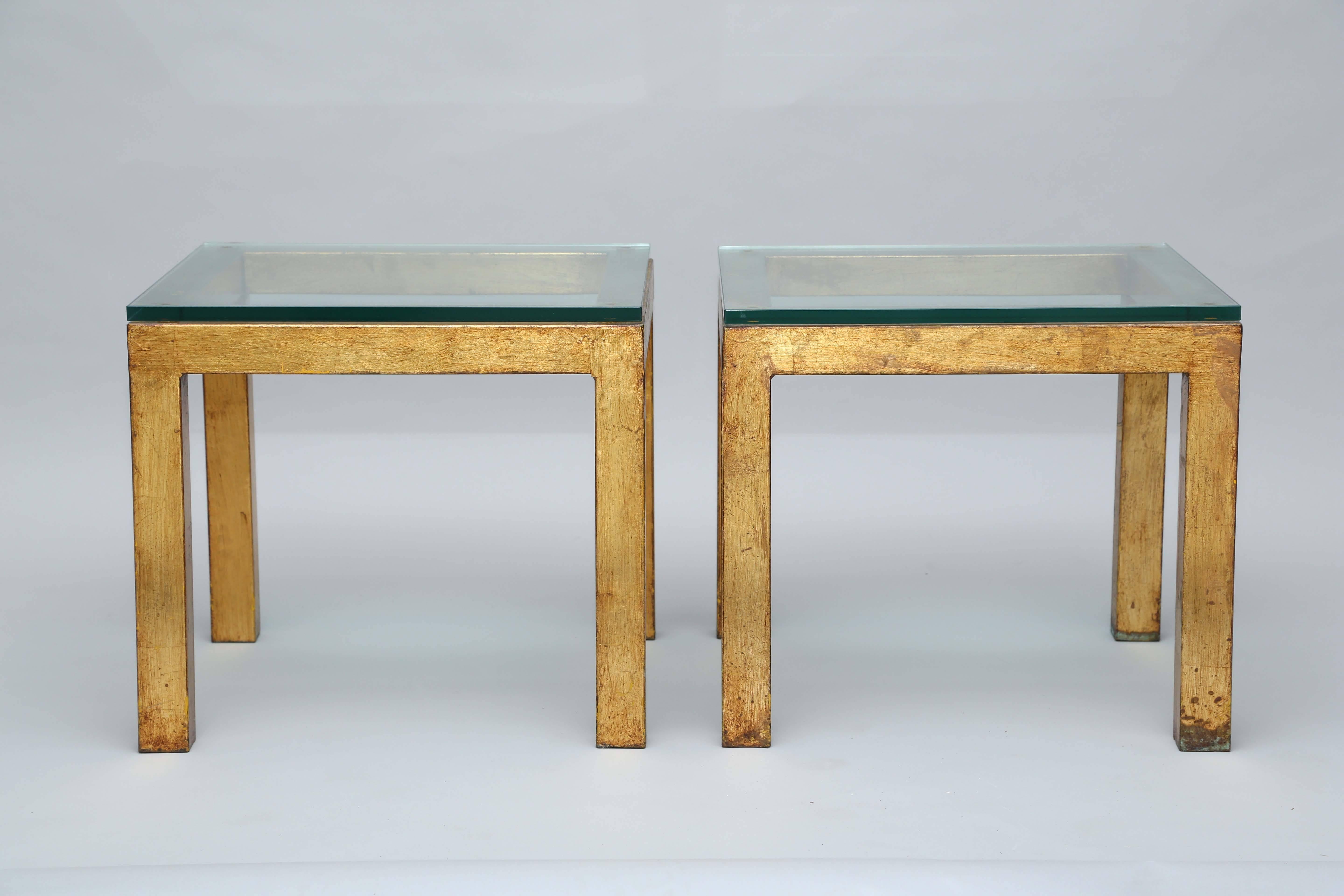 Pair of side tables, in the modernist Parsons form, of metal with gilded finish, having a glass top.

Stock ID: D9328