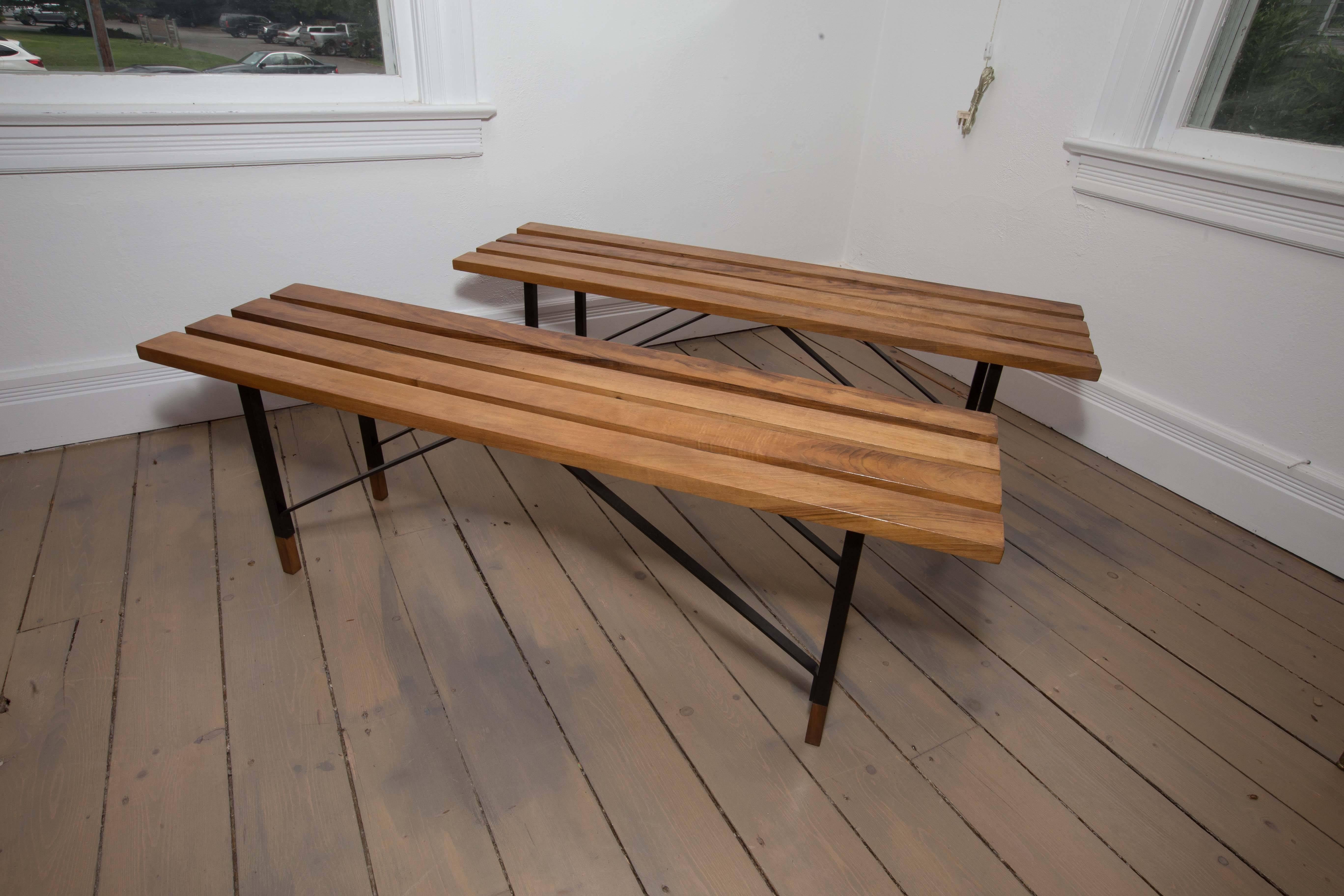 Wood slat bench with black metal cross bar base and wood feet.