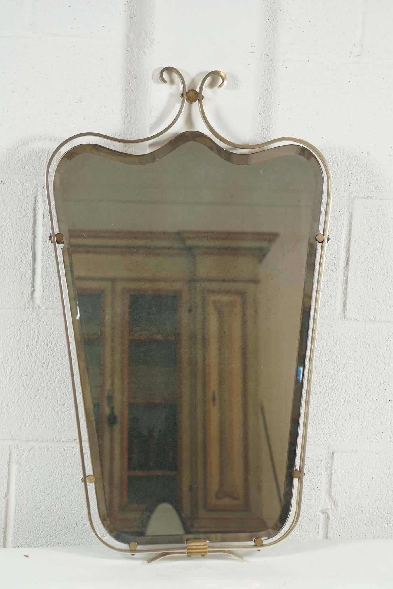 Here is a chic small-scaled French mirror in brass with a fogged beveled mirror.
The mirror is inset to the circular clips inside the frame.