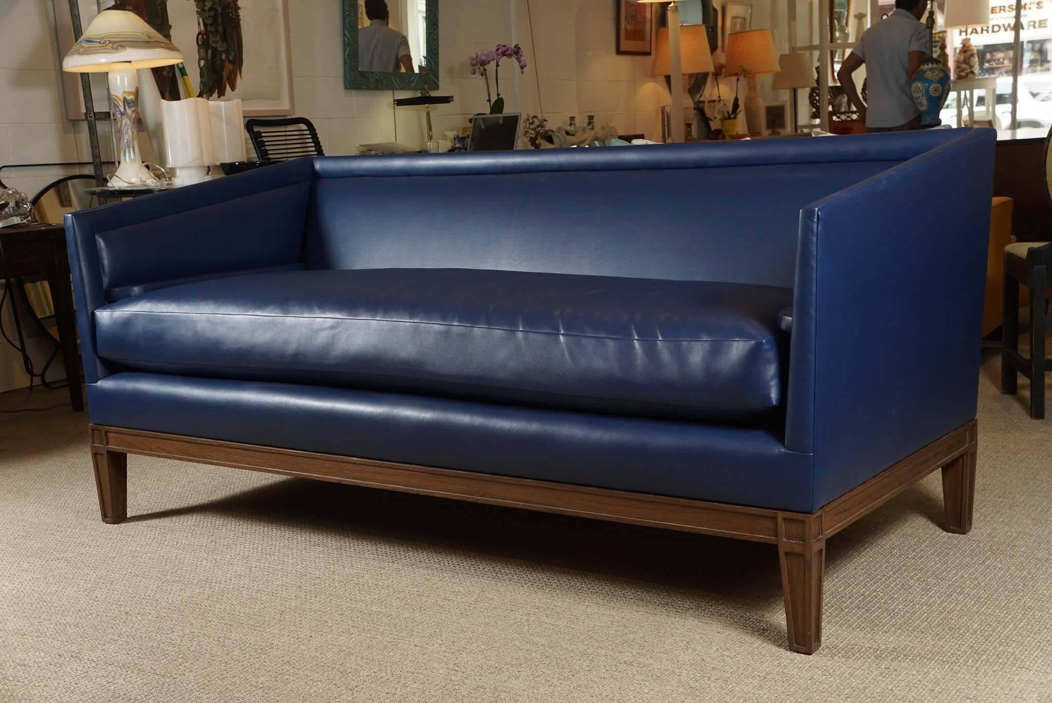 Here is a great boxed arm sofa in a blue faux leather with inset arms. The sofa is custom-made based on an original 1940s French Moderne sofa. The thick seat cushion is very plush. The wood finish is a medium walnut.