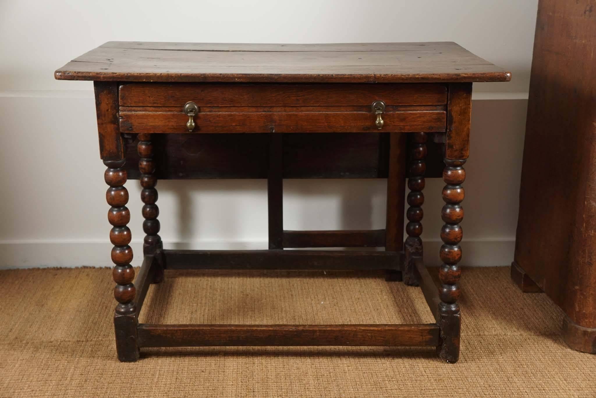 19th century, oak, gate leg table, with hand-turned spool legs and joined by stretchers. One long drawer, with brass, tear-drop hardware, adds to this wonderful tables charm.