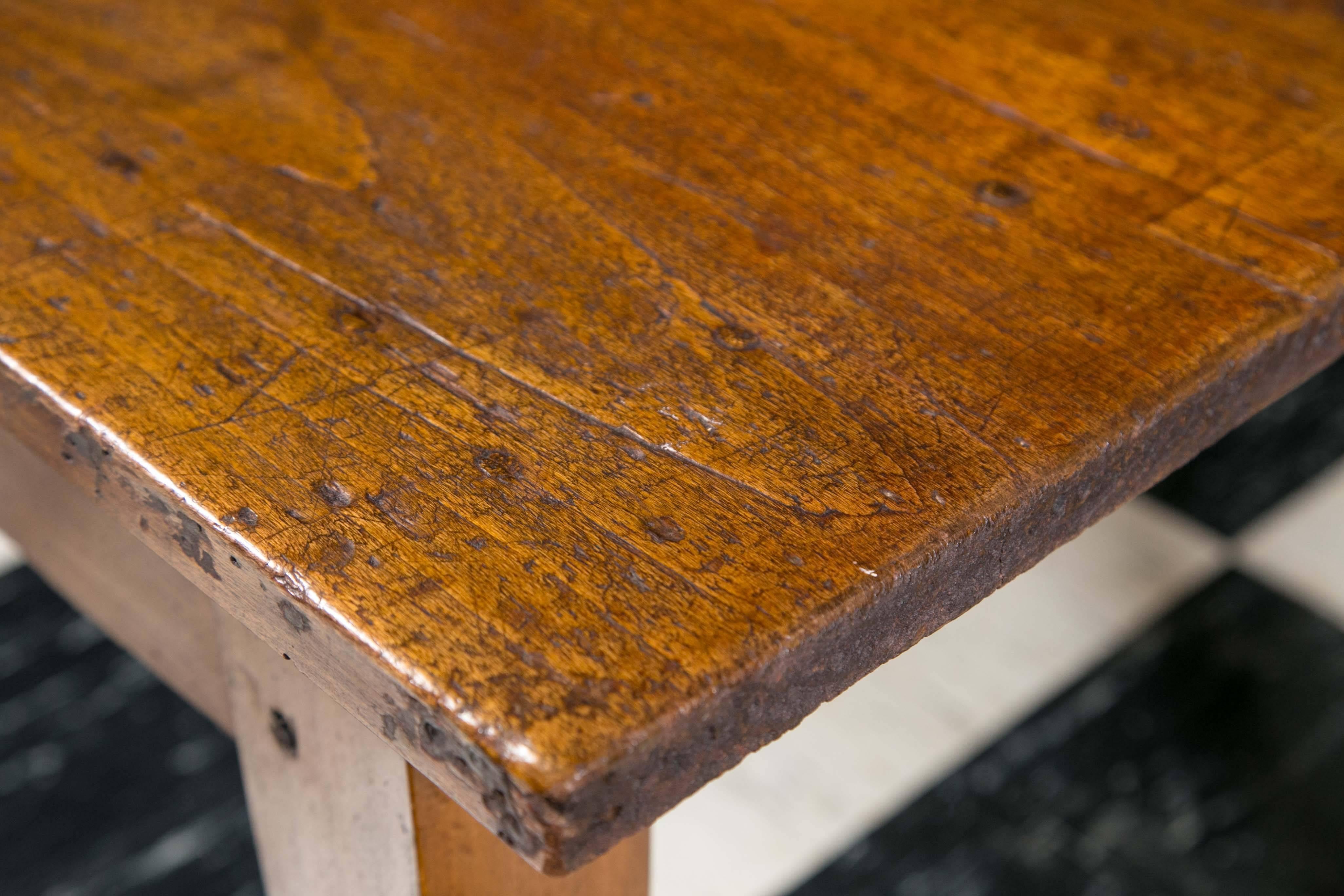 19th century French farm table in poplar. Thick, three-board top rests on sturdy tapered legs. Period peg construction. Aged top gives great character to the table.