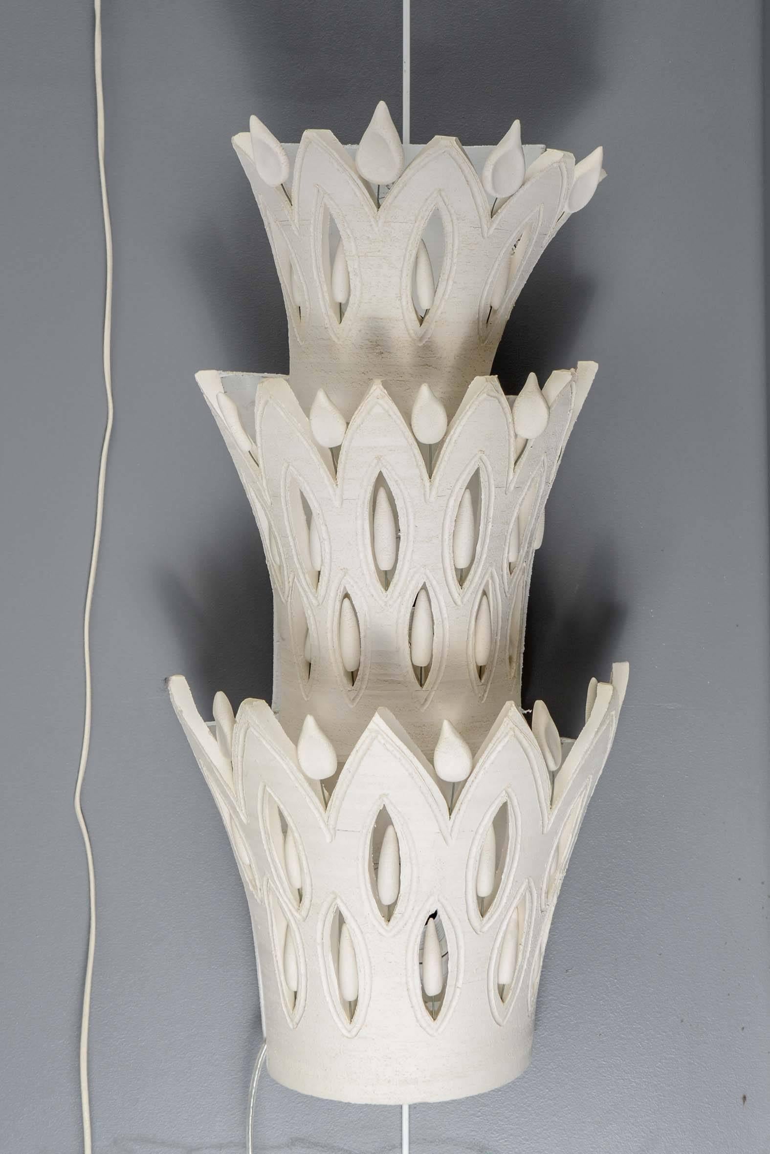 Pair of beautiful ceramic wall sconces by Georges Pelletier.

Three stacked ceramic sconces on painted wood panel.
