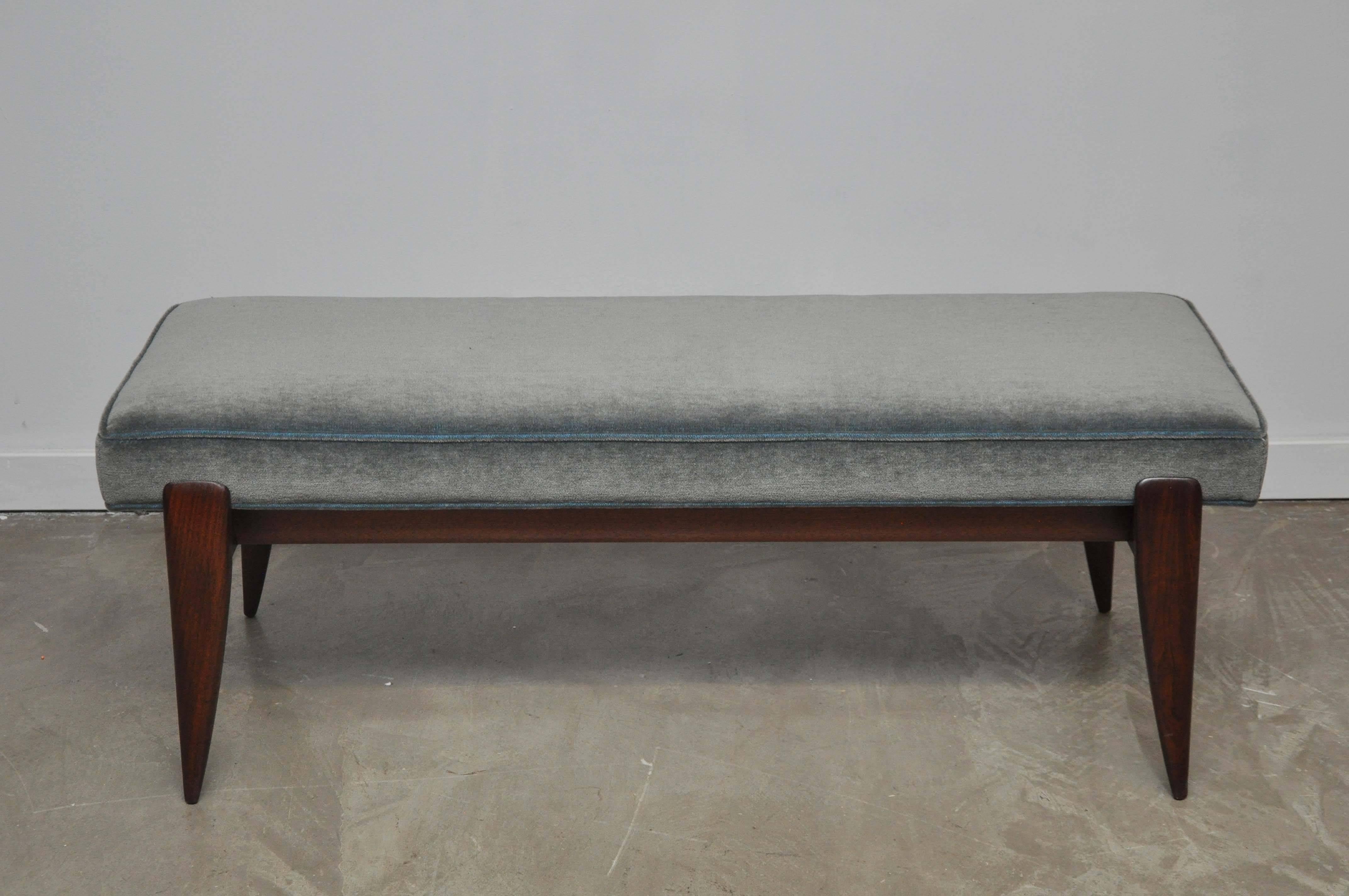Beautiful bench designed by Gio Ponti for M. Singer and Sons. Fully restored. Sculptural walnut base with new blue/grey mohair upholstery. Original label present on underside.