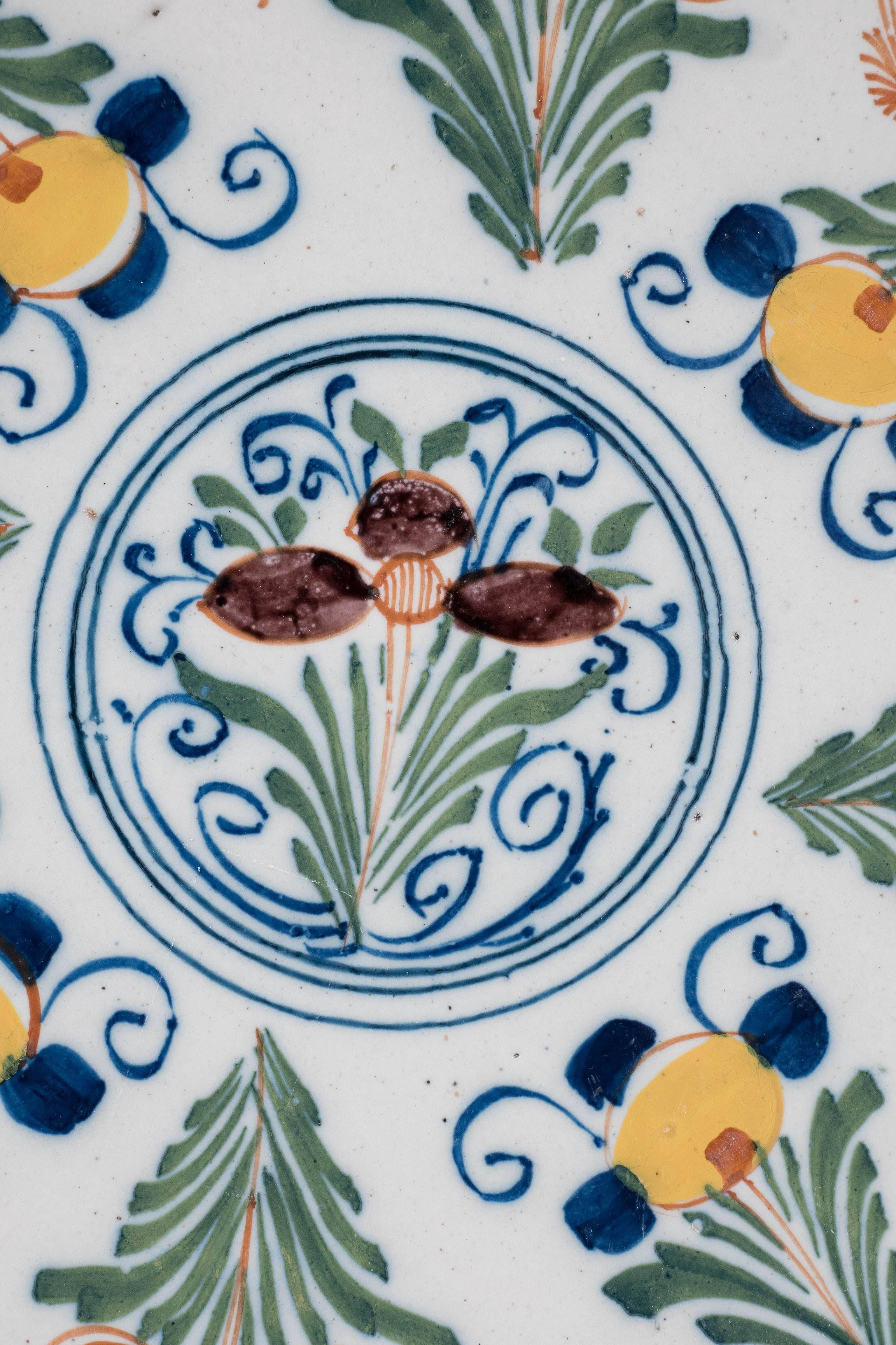 A pair of 18th century Dutch delft pancake plates beautifully painted 
with flowers and scrolling vines in a circle around a central rondel. Spruce green, yellow, and manganese enliven the design.
 