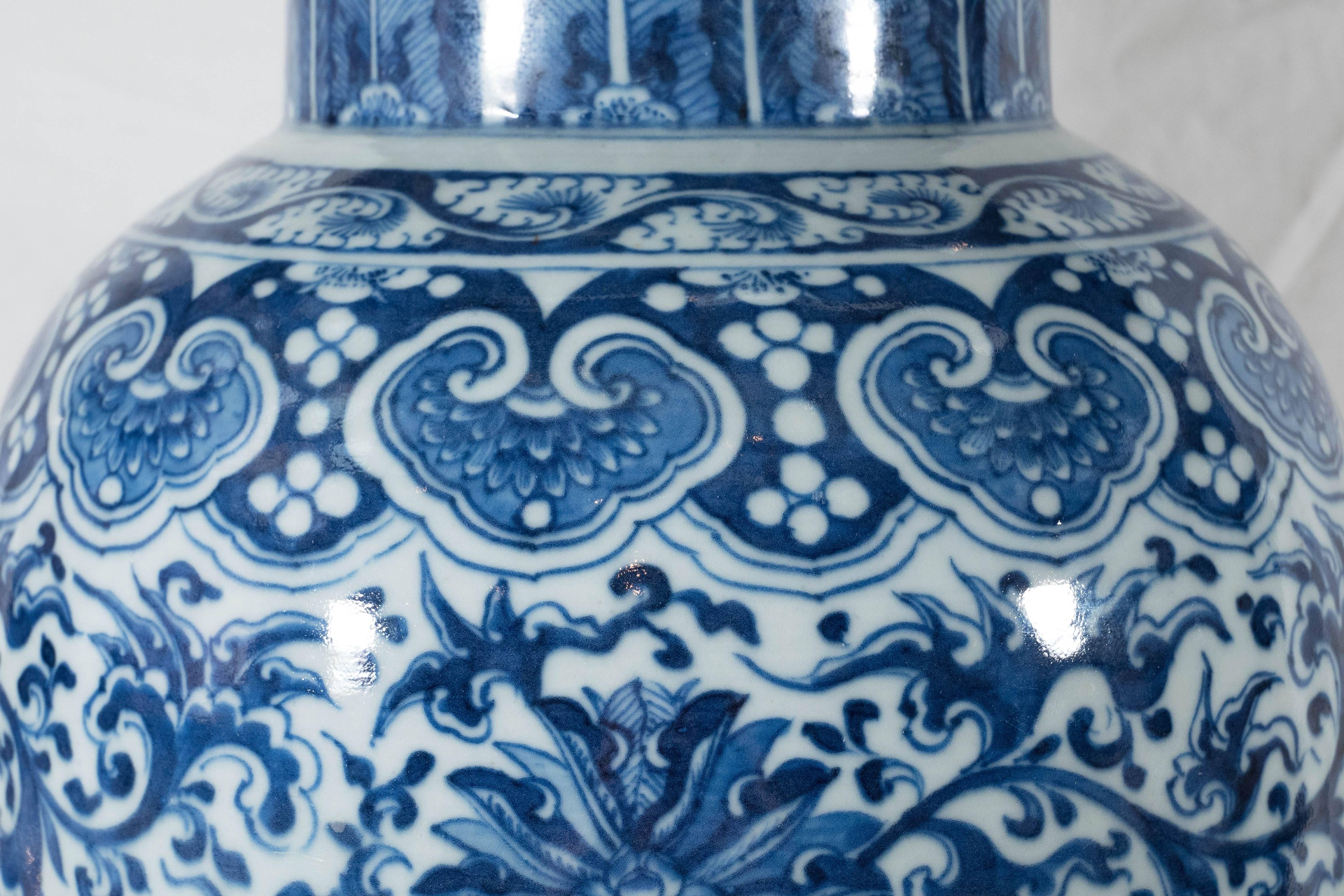 A pair of beautiful Chinese blue and white porcelain vases each hand-painted in cobalt blue with traditional Kangxi design showing scrolling lotus between bands of cloud collars. The form is tall and slender. The neck decorated with acanthus leaves.