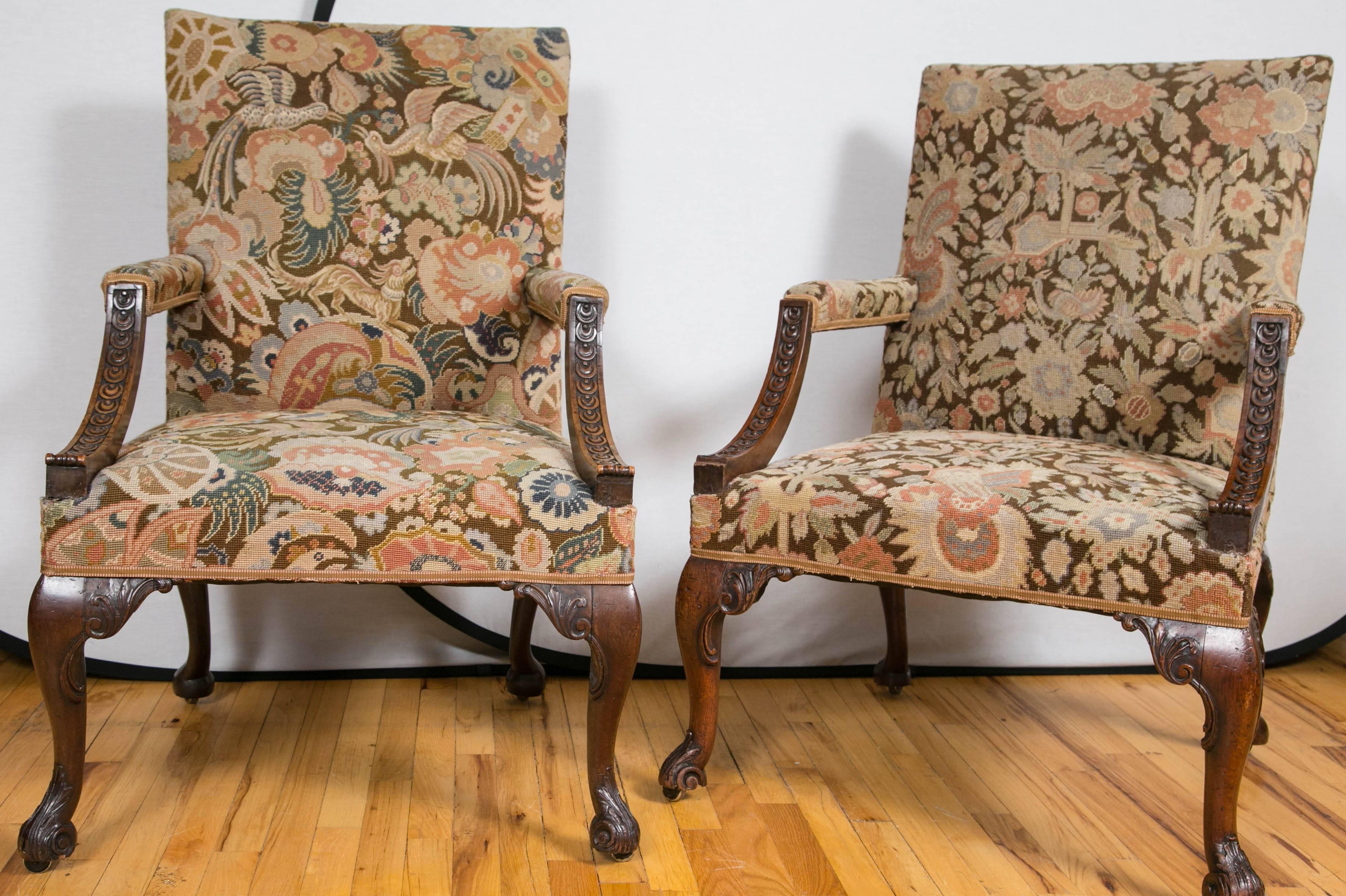 A pair of large late 18th century upholstered armchairs. Each with rectangular backs issuing padded armrests with foliate carved uprights. The seats are raised on front cabriole legs finely carved with foliate sprays and terminating in scroll-form