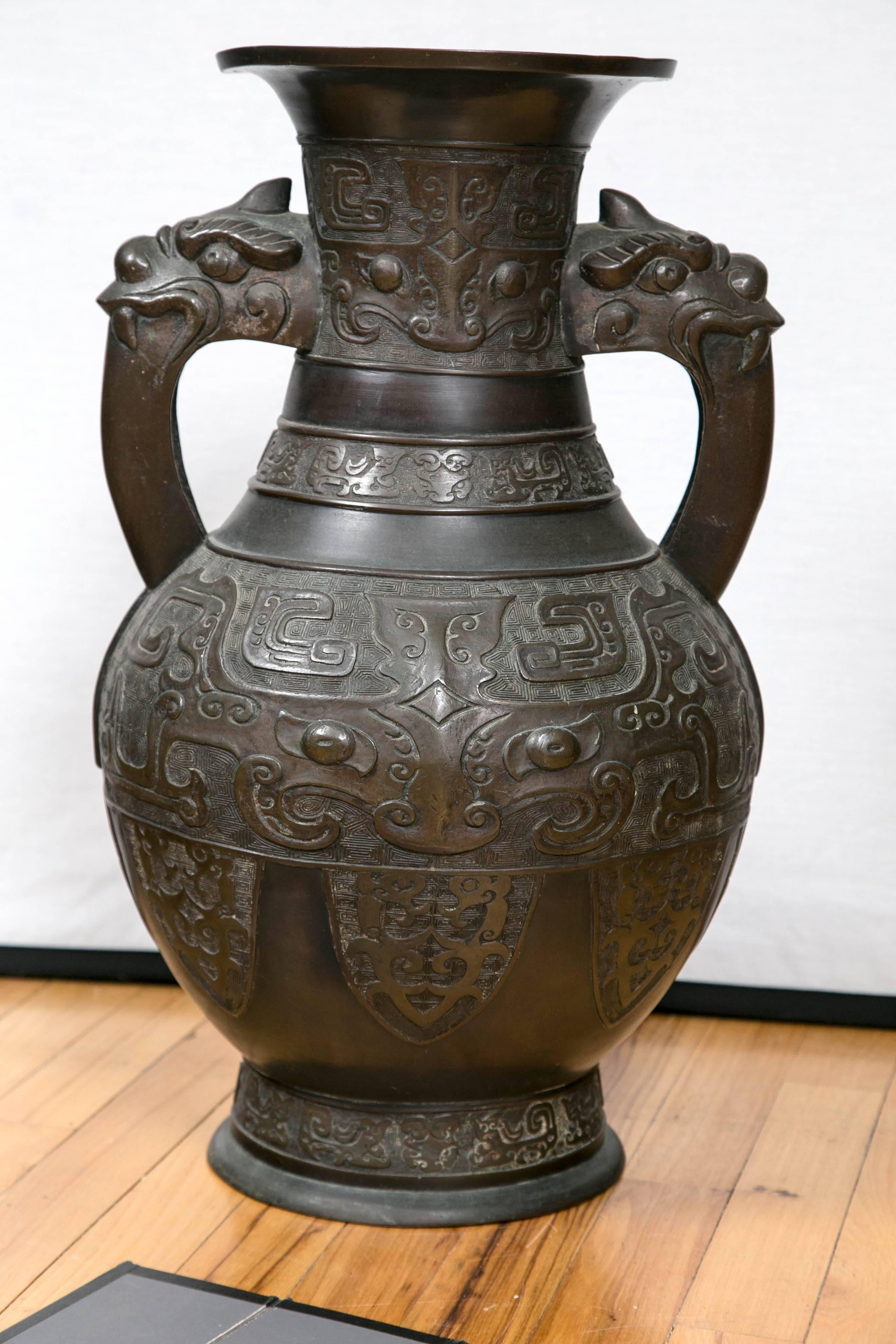 Vase chinois en bronze avec une décoration dans le style archaïsant et des anses en forme de dragons et de bêtes mythiques.