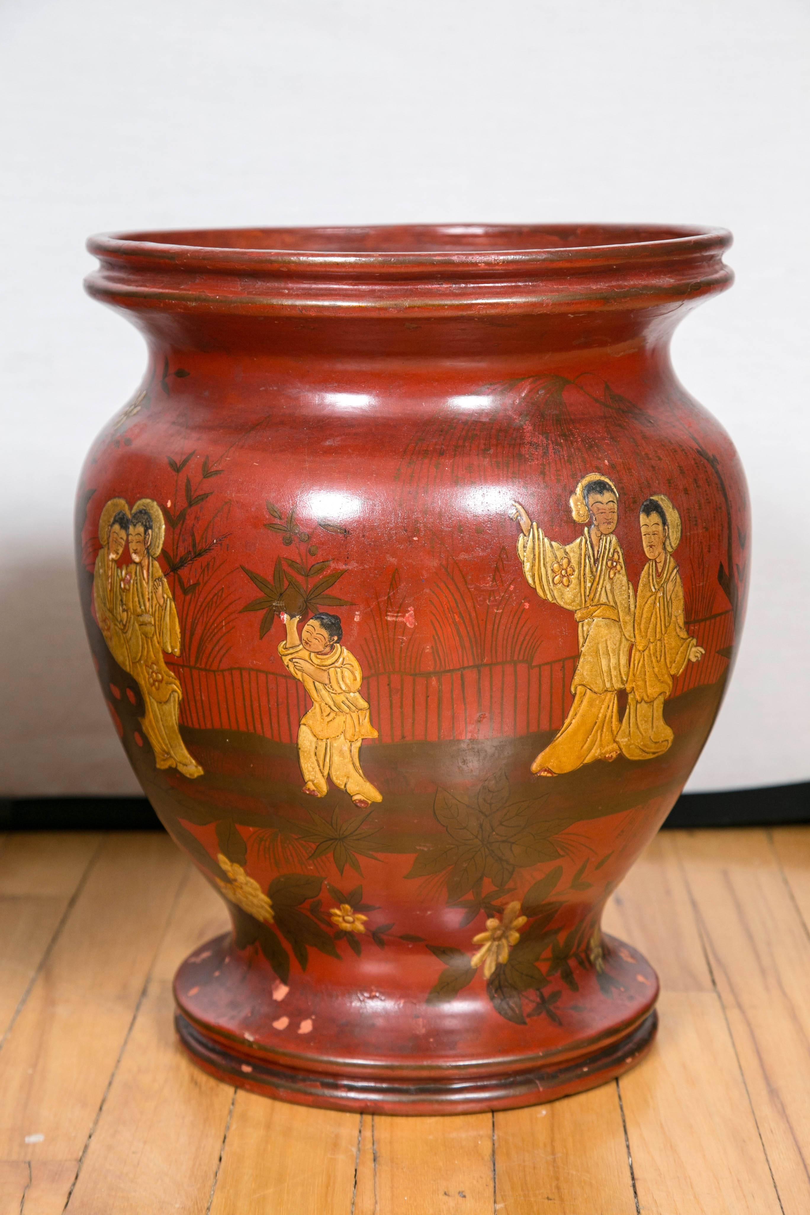 A decorative pair of red lacquered terracotta baluster form vases with ribbed tops. Hand-painted chinoiserie design with stylized landscape scenes and gilt figures. One is lined with zinc while the other shows small remains of its original zinc