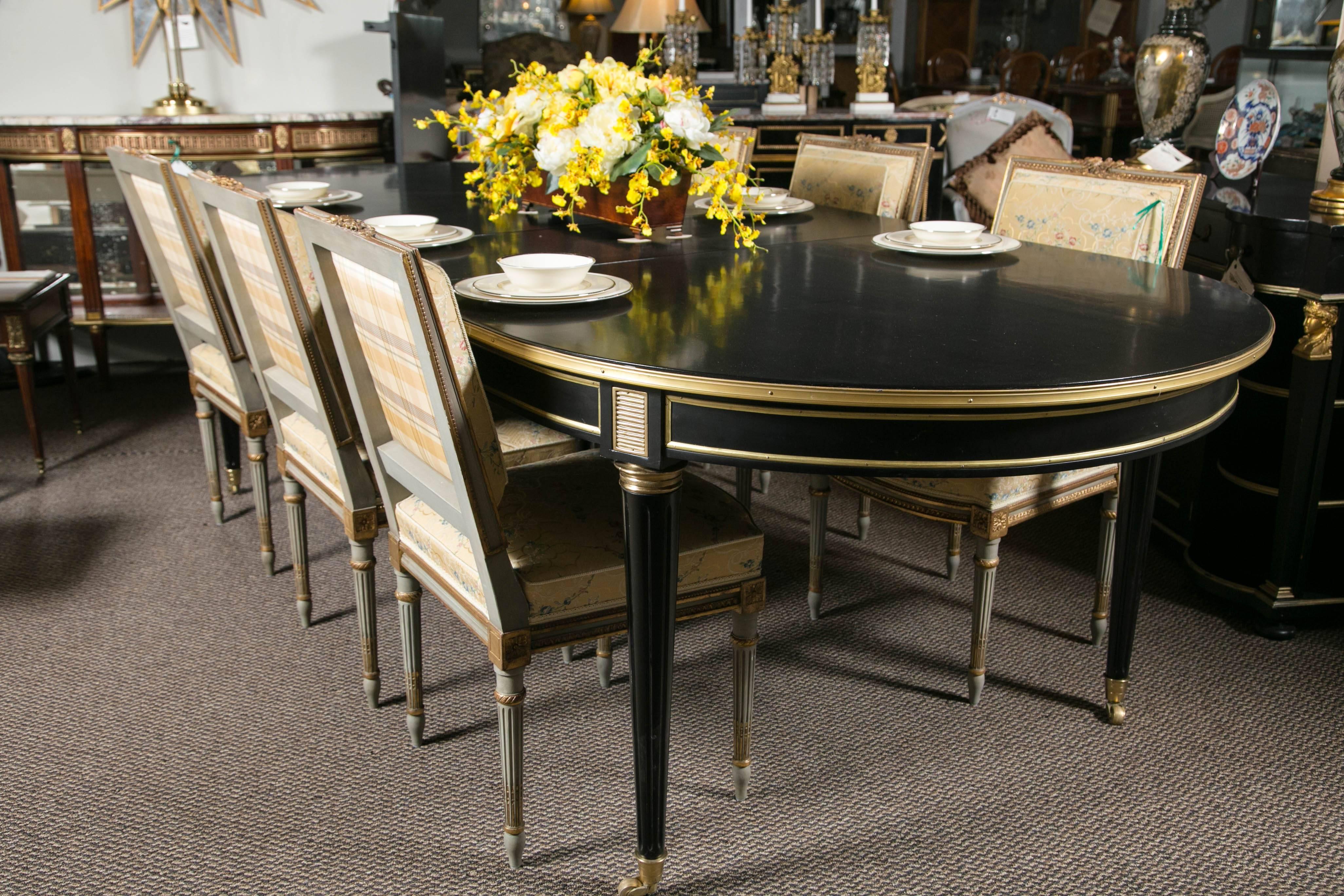 A fine ebony bronze-mounted dining table in the Louis XVI fashion attributed to Maison Jansen. The bronze casters and sabots leading to a tapering reeded legs terminating in a bronze capital. The gilt bronze framed apron having bronze cookie cutter