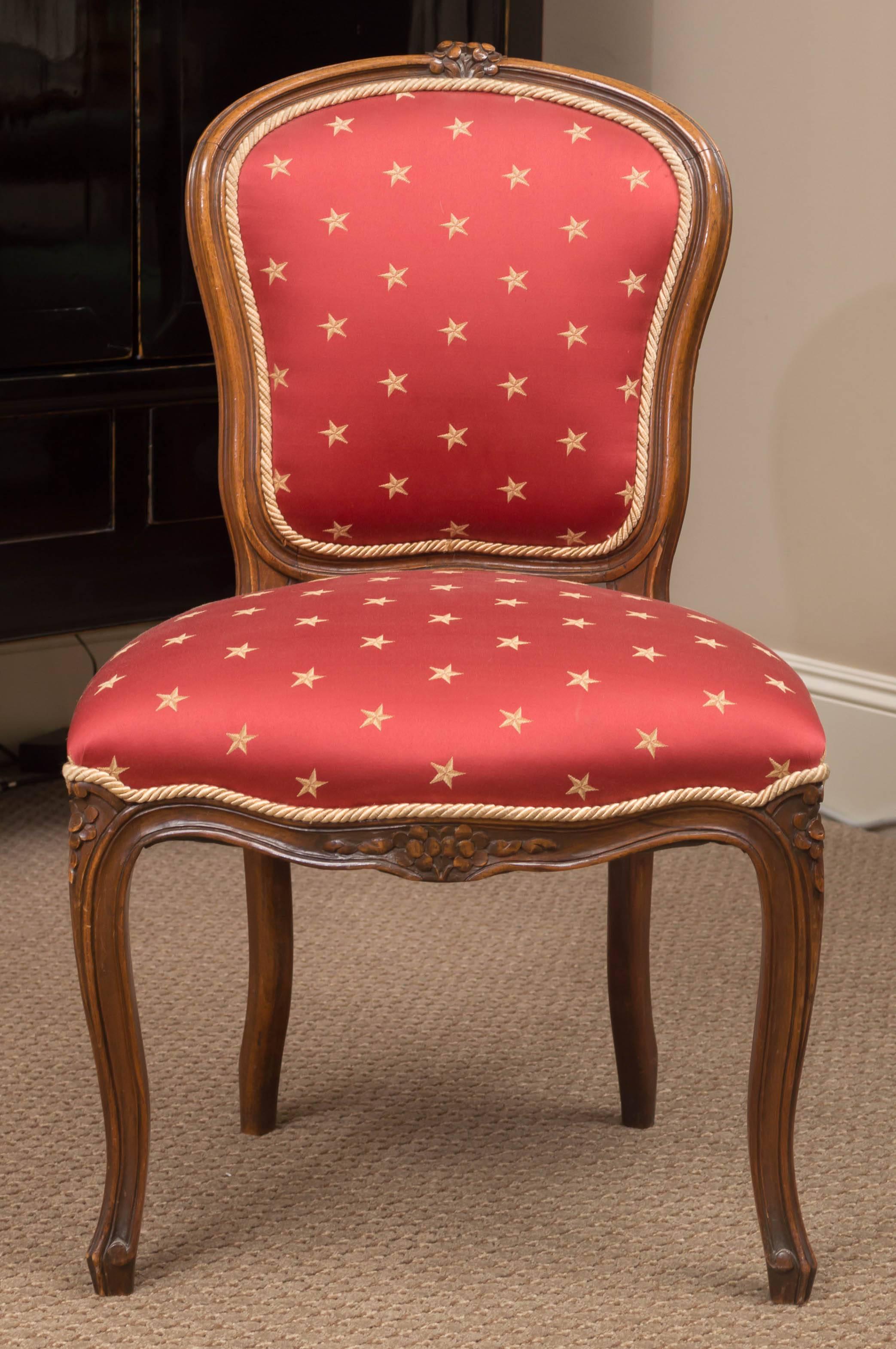 The carved and padded backrest over a shaped seat above a floral carved seat rail raised on cabriole legs. Covered in red silky fabric with gold stars and small gold roping trim.