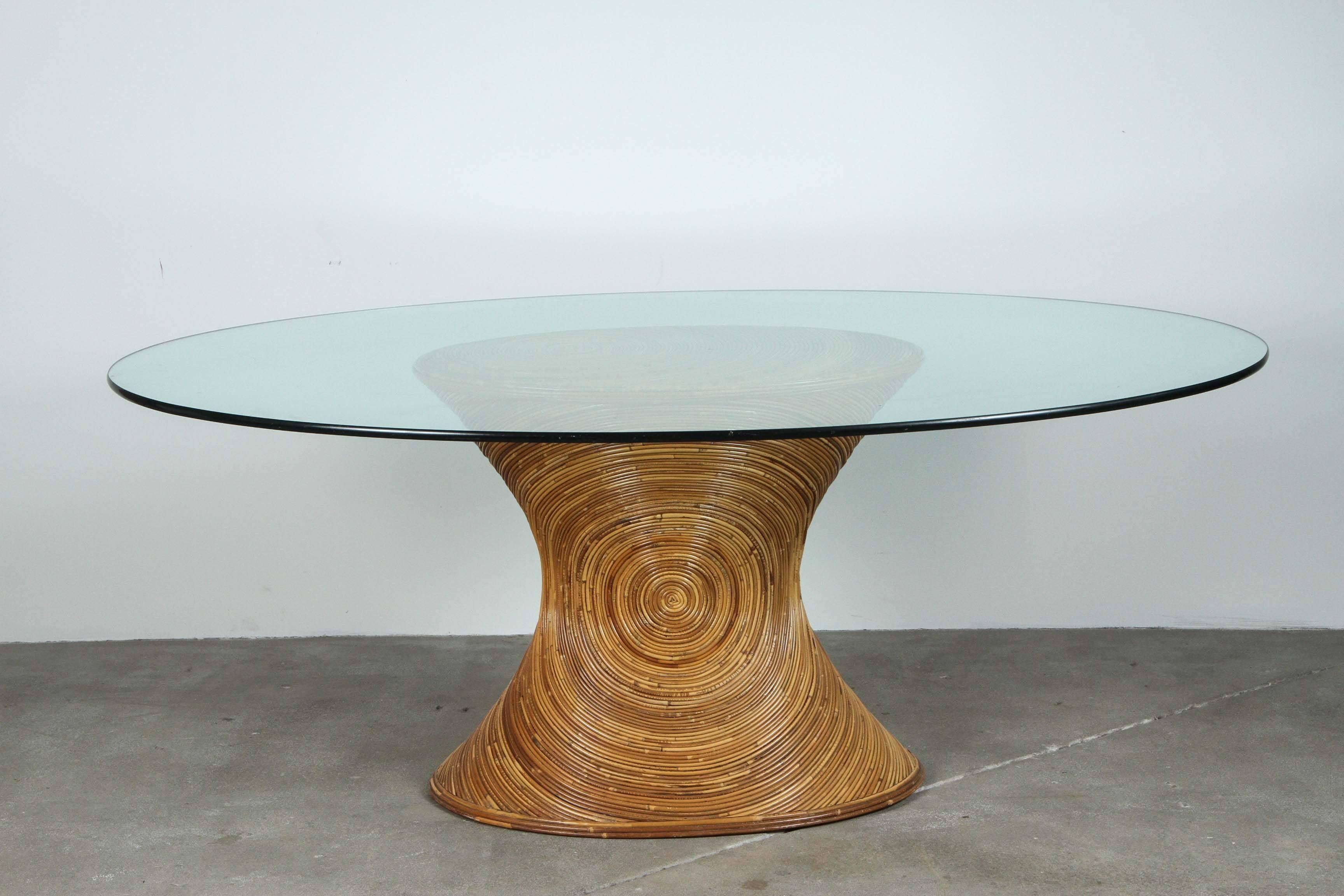 Oval glass top with an rattan base in the style of Gabriella Crespi.