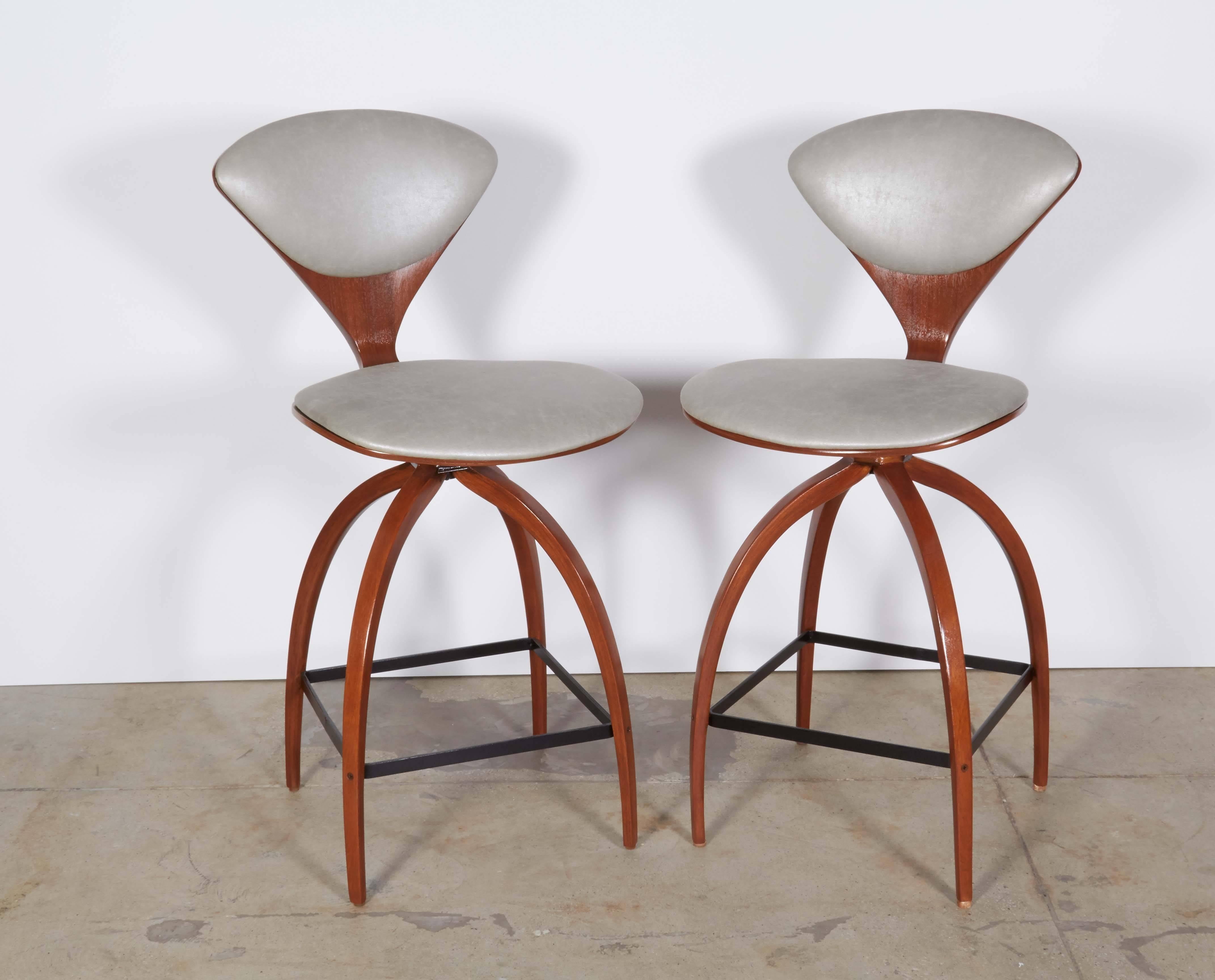 Early edition pair of Mid-Century classic bar stools with bentwood frames and iron stretchers. Stools have been mint restored and feature new padding and upholstery in a neutral light gray coated cotton.
