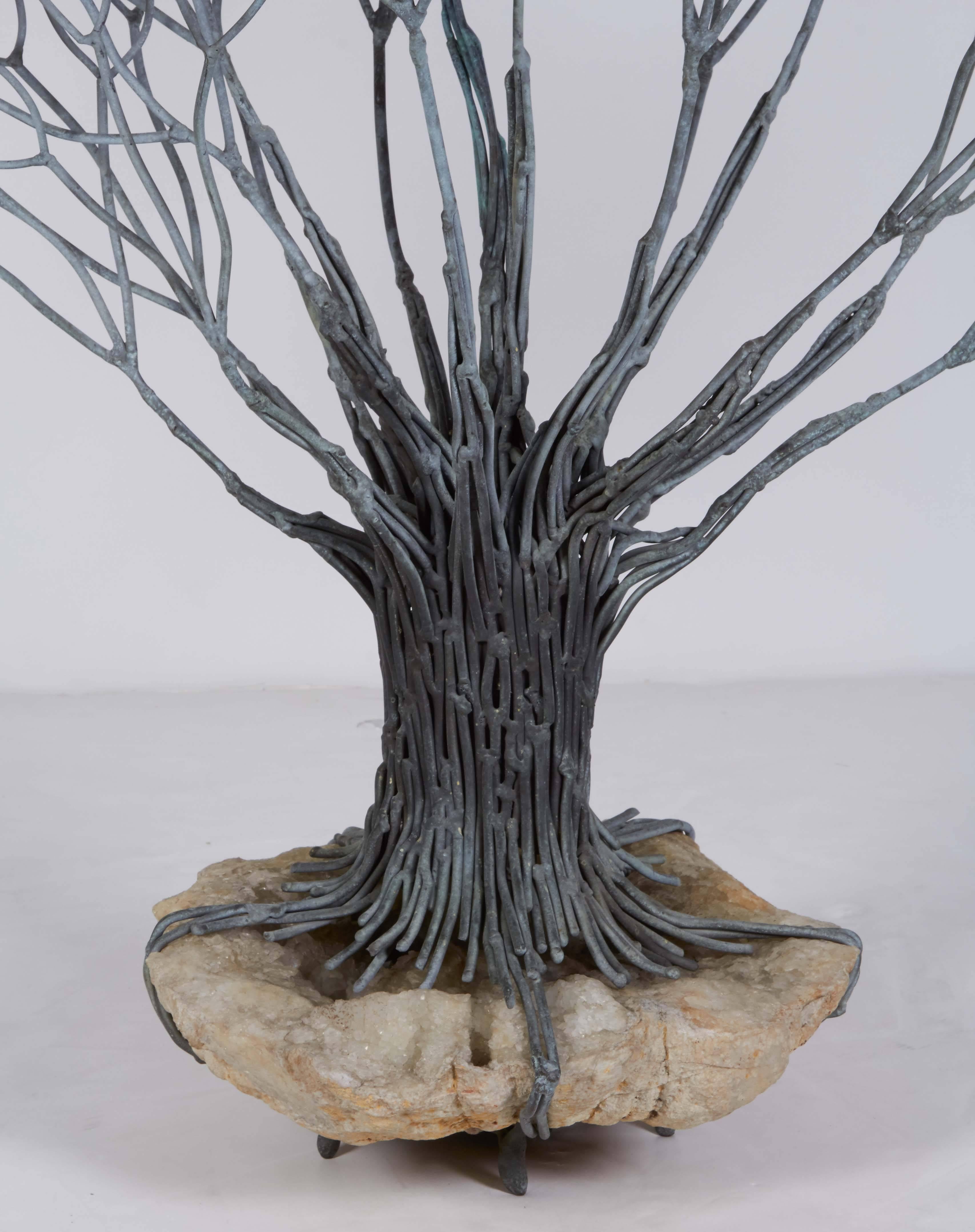 The bronze tree has roots growing around a geode.