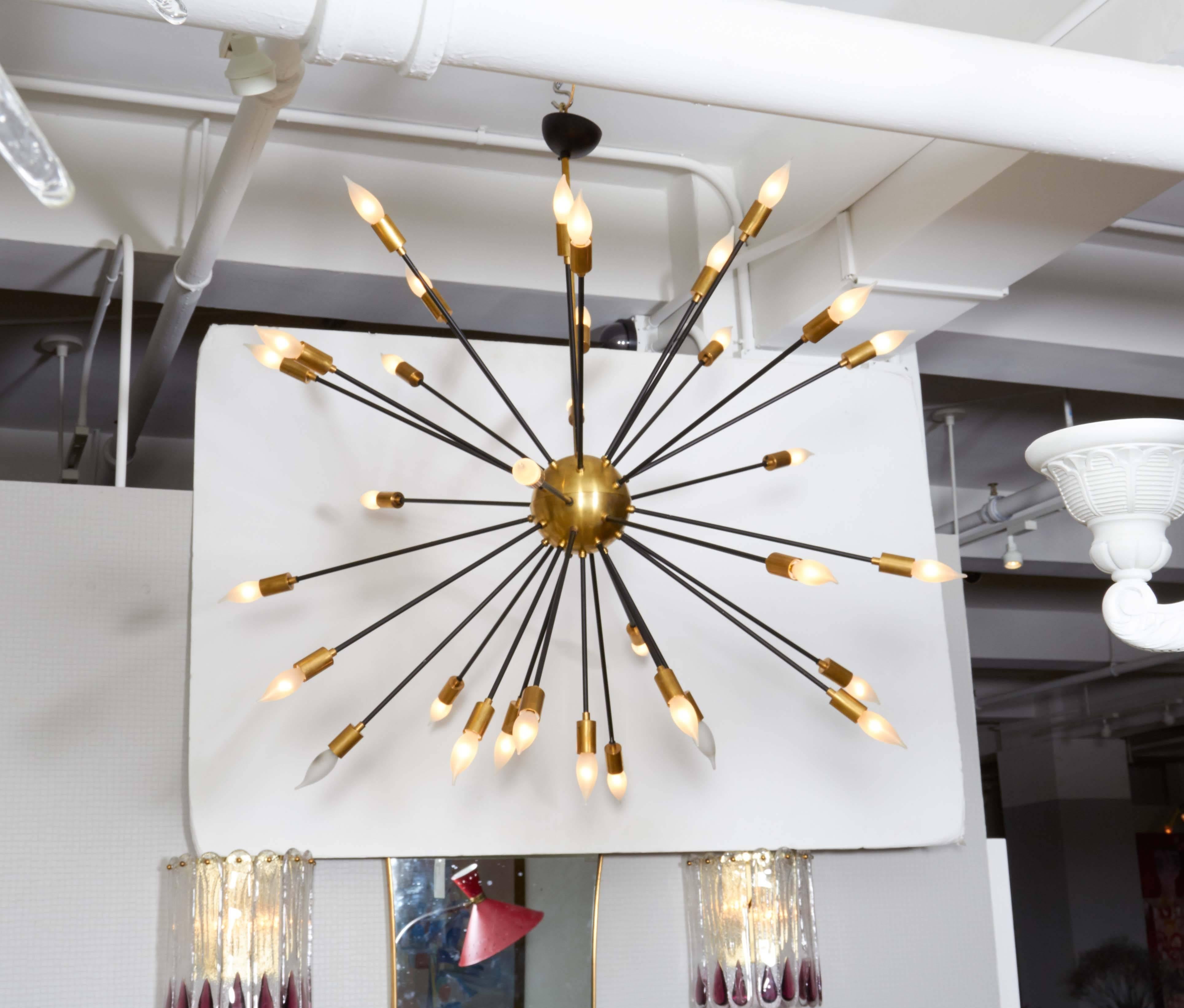 This chandelier has a gold brass sphere with 32 black lacquered rays each one ending with a gold brass lamp holder.