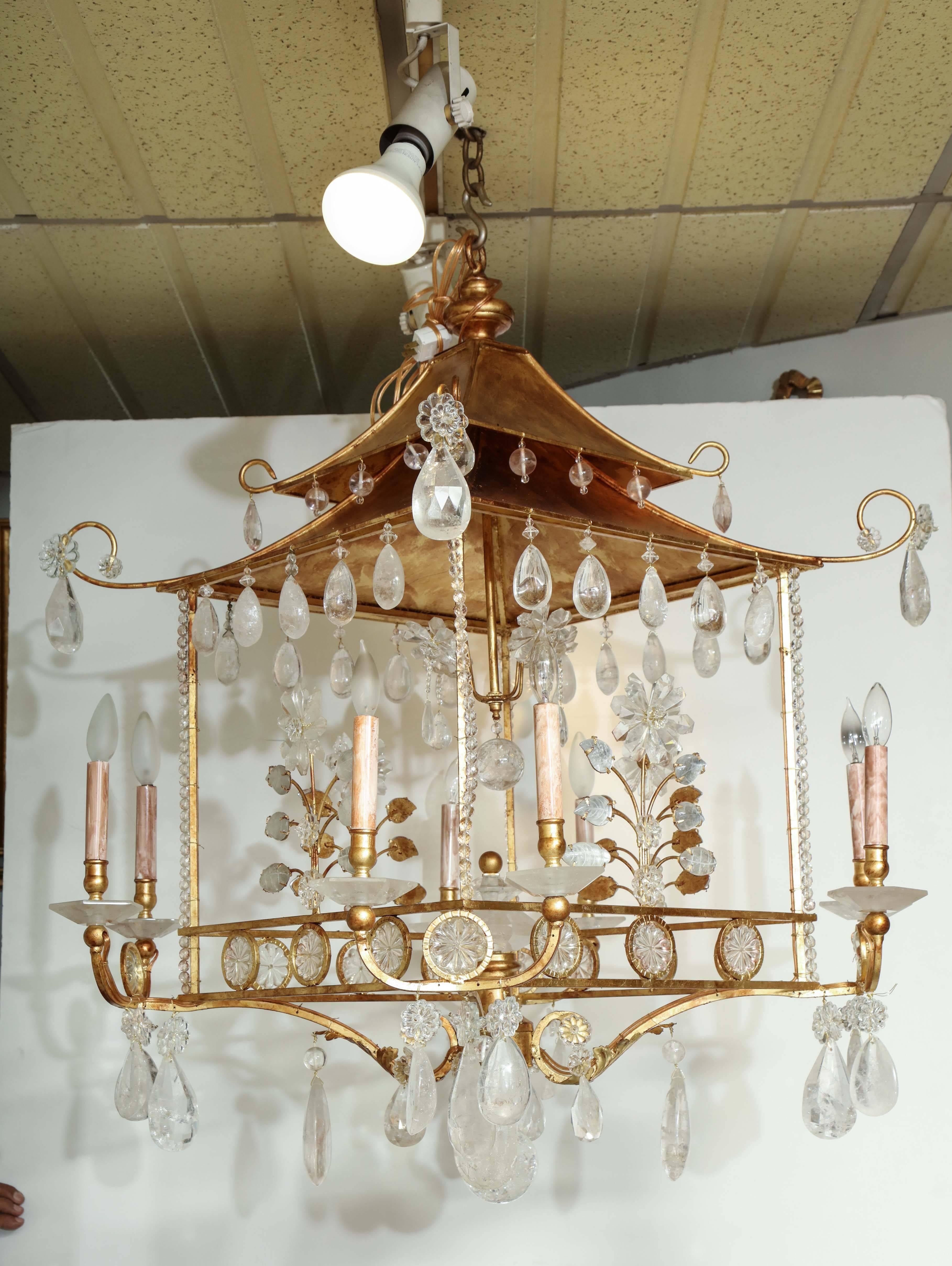 A gold leaf pagoda-form eight-light chandelier decorated with carved rock crystal flowers and leaves and having cabochon rock crystal pendants.
