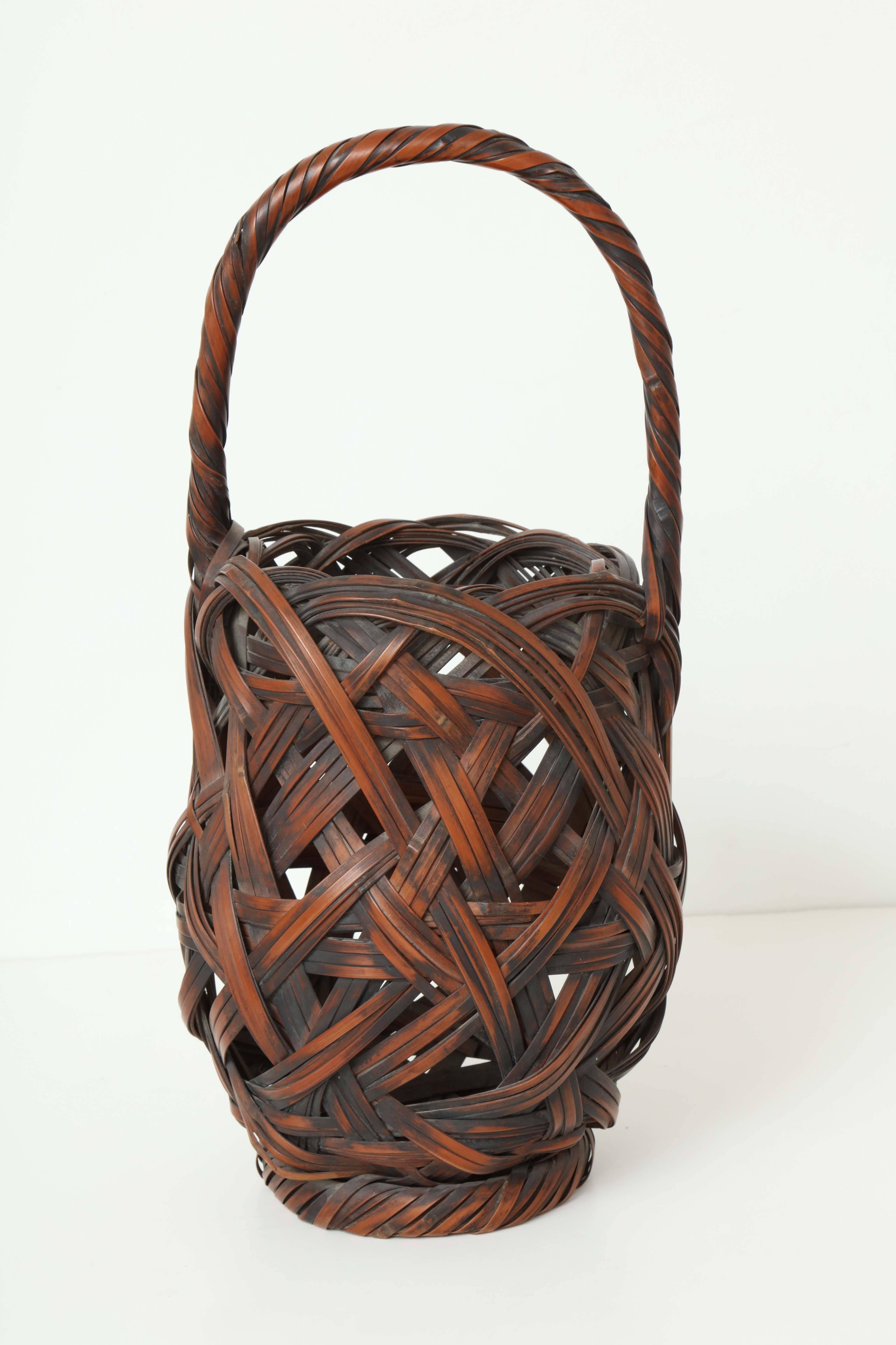 A Japanese Meiji period woven bamboo basket with upright integral handle and fine patina.