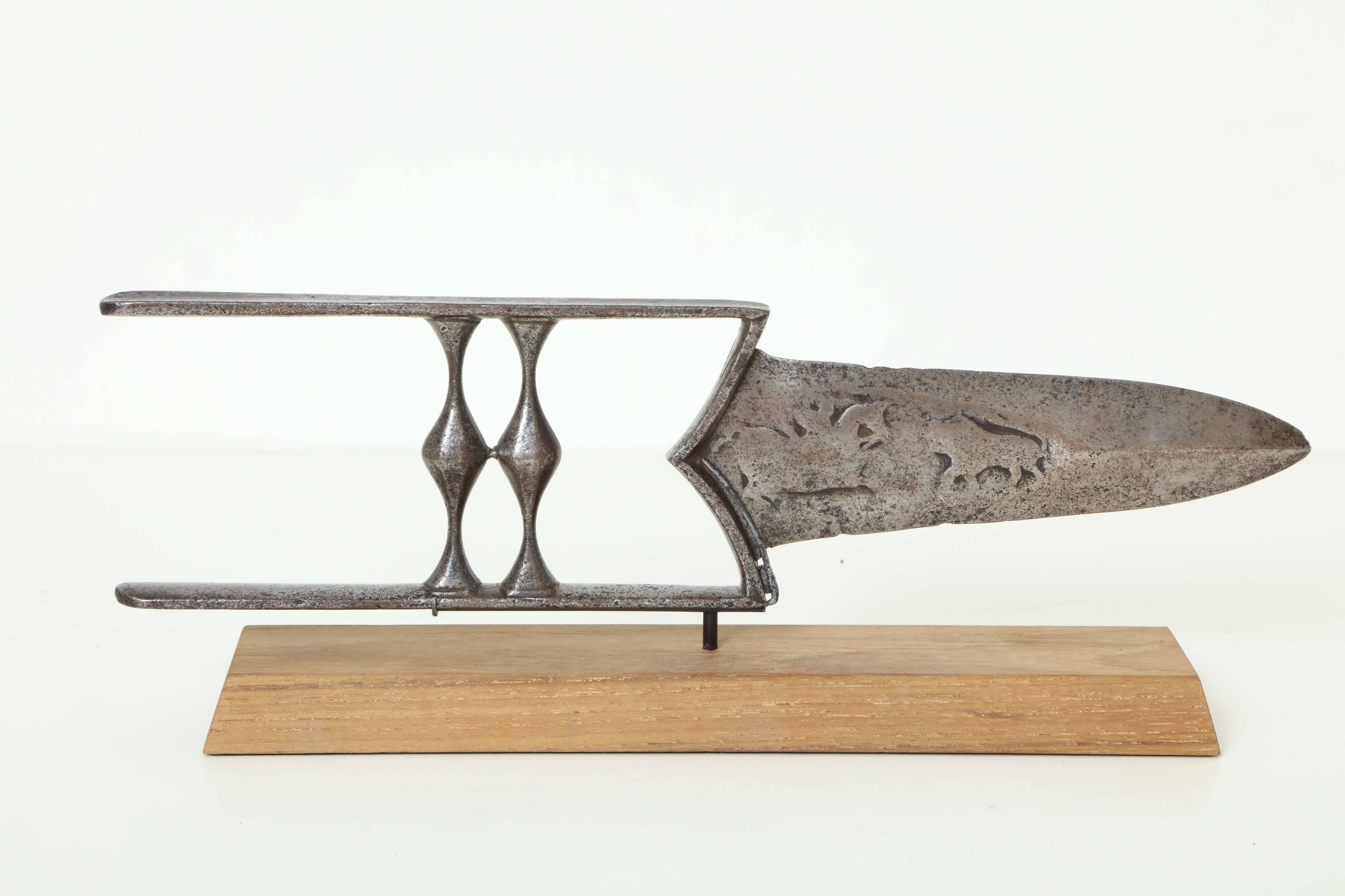 A 19th century Indian steel Katar (push-dagger) with raised figural animal decoration to the blade, mounted on a contemporary chamfered oak base.