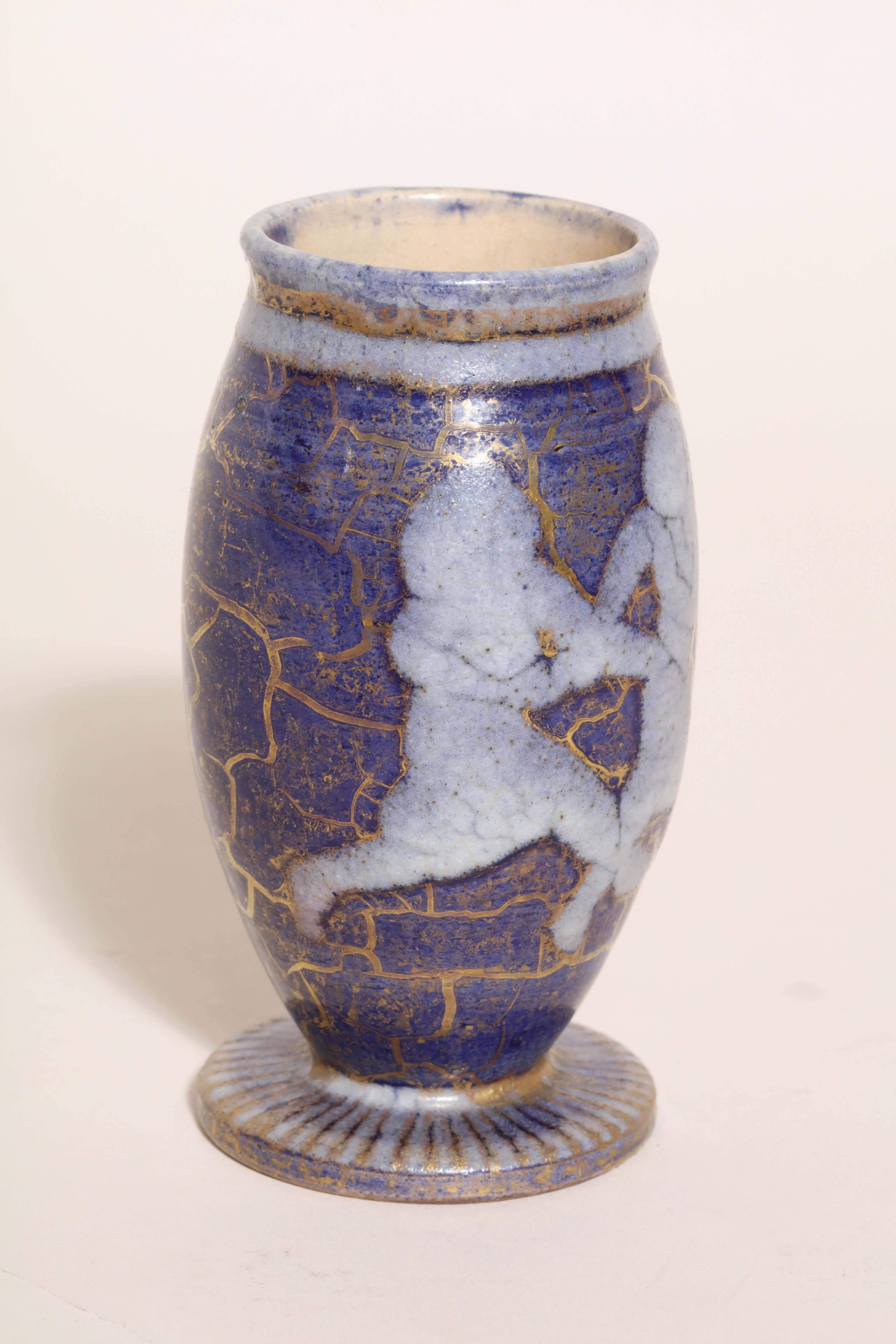 This small vase has two figures in action on a blue and gold ground.

Jean Mayodon was trained as a painter, but became a ceramist with a painter's mind. He produced figurative decorated pottery after the antique tradition characterized by the
