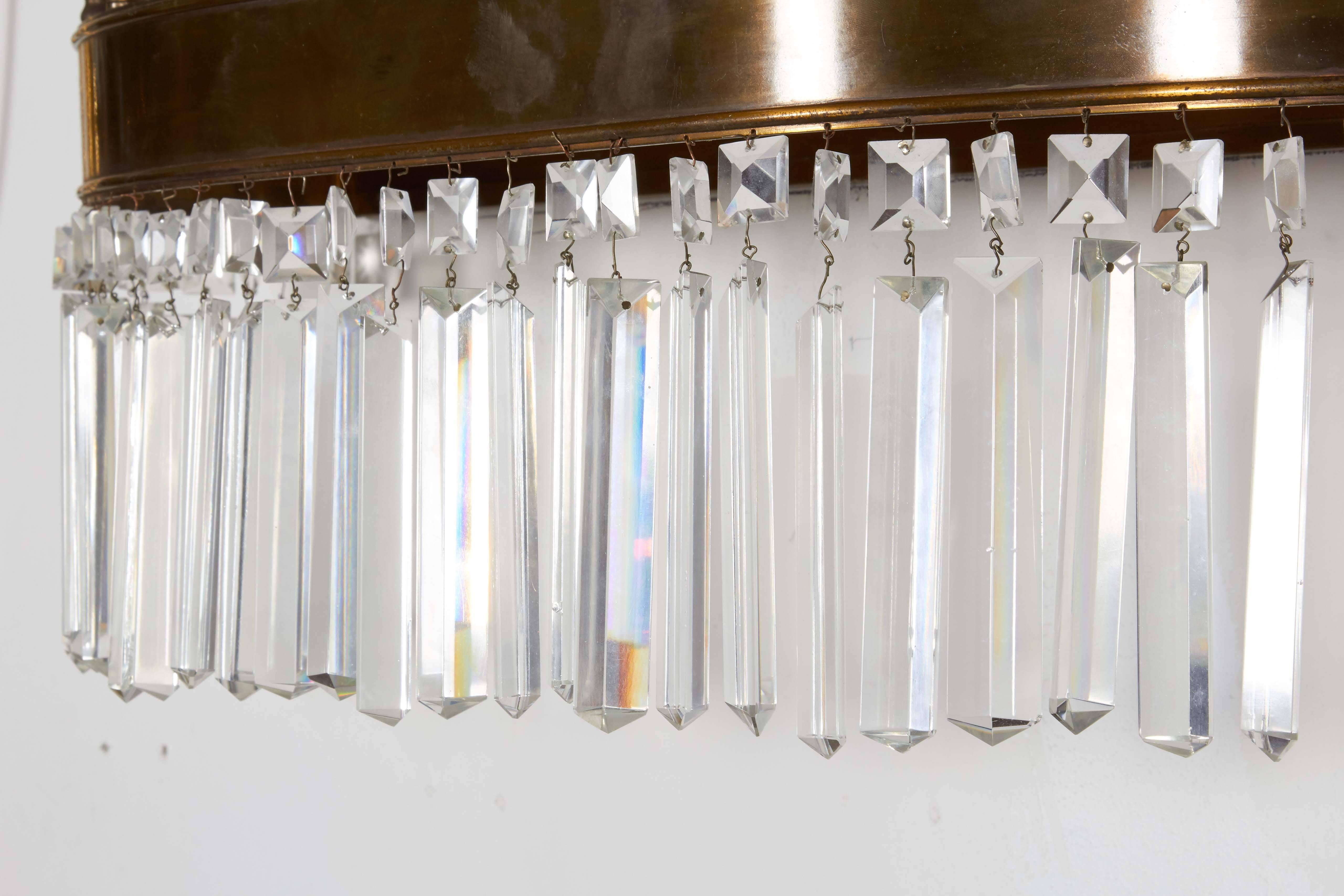 A large vintage wall light, including five lights, each with rounded glass shade, mounted on a brass demilune frame, trimmed with crystal prisms and pointed finials. Despite minuscule presence of chips to original crystals, this fixture remains in