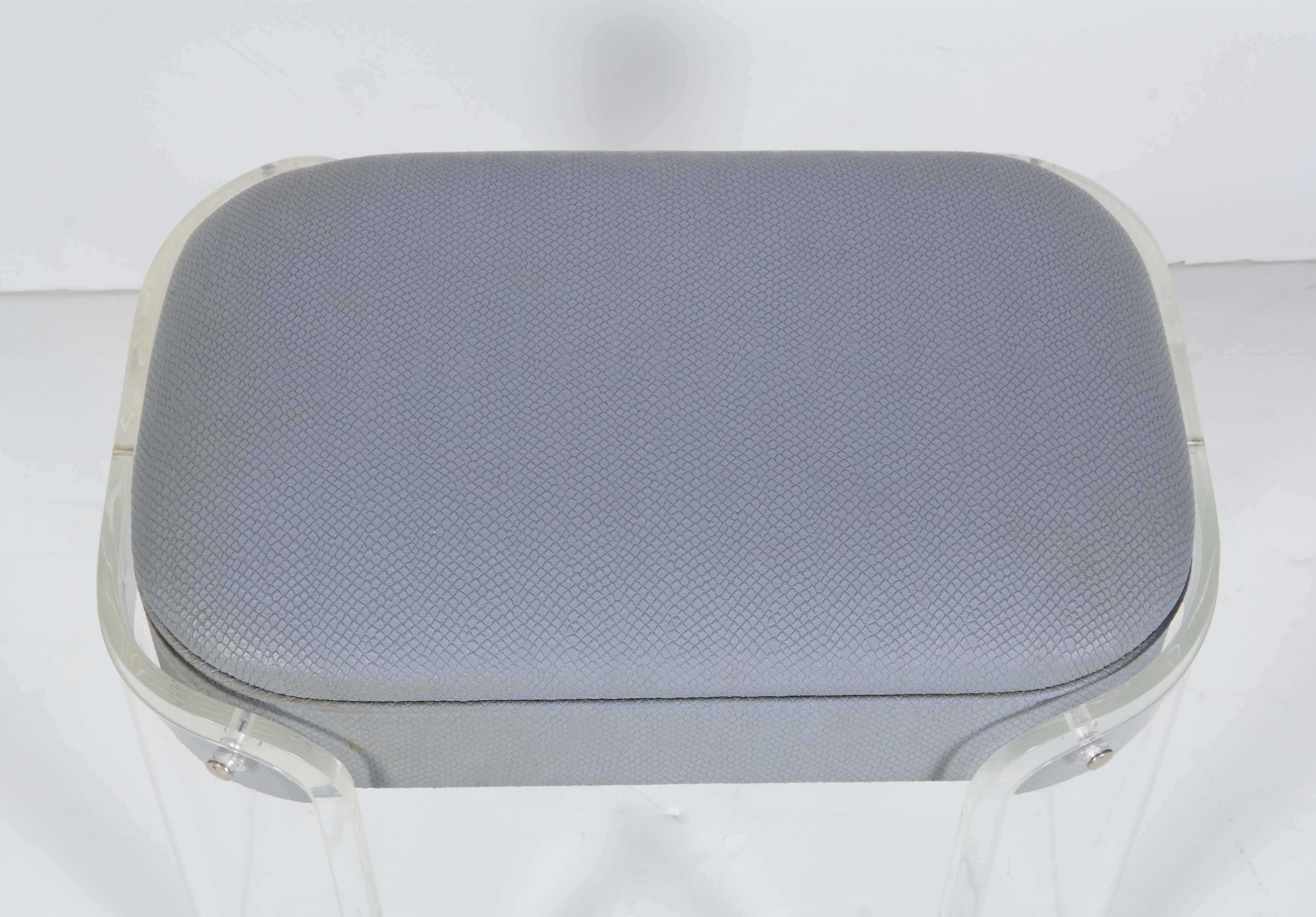 A modernist vanity stool, produced circa 1970s by Hill Manufacturing corp, including cushioned vinyl seat, embossed with snakeskin pattern, on curved Lucite base. Markings include manufacturer's label, beneath the seat. Very good condition, wear