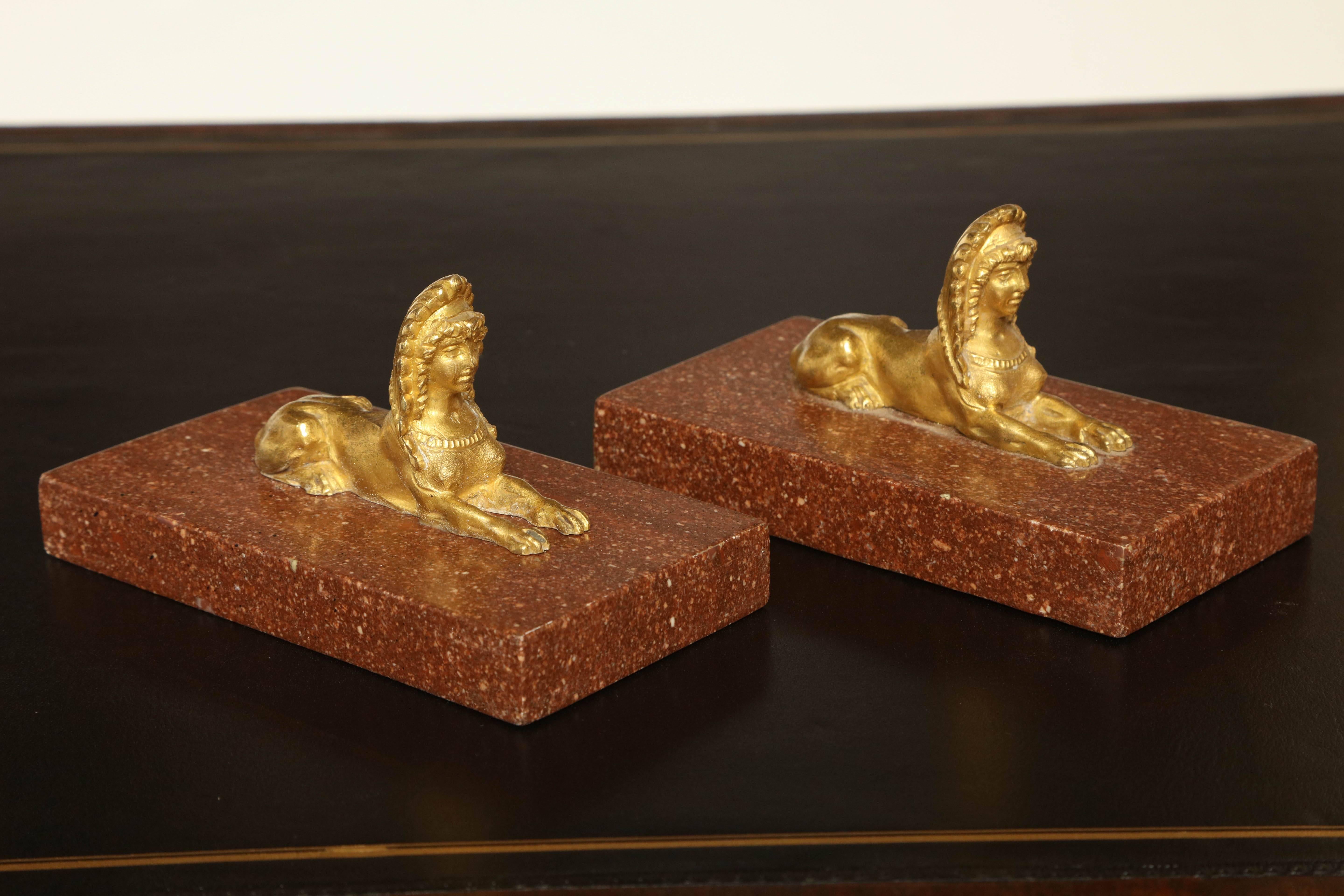 Pair of gilded bronze sphinx on porphyry bases.