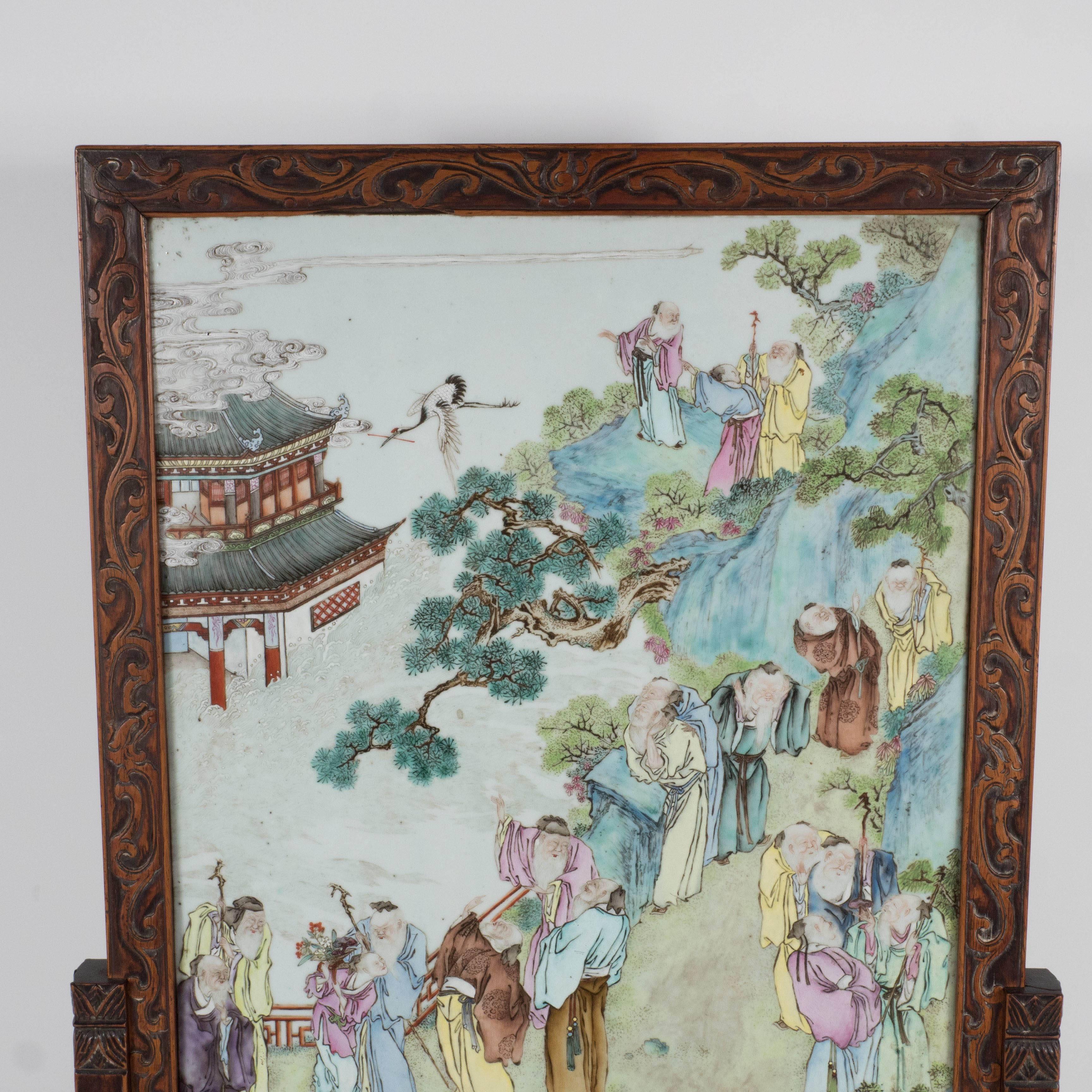 This exquisite table screen is made of hand-carved rosewood framing an elaborate Chinese export porcelain panel of a Chinese court scene. The rosewood frame features a meandering border pattern. The export porcelain panel is hand painted and quite
