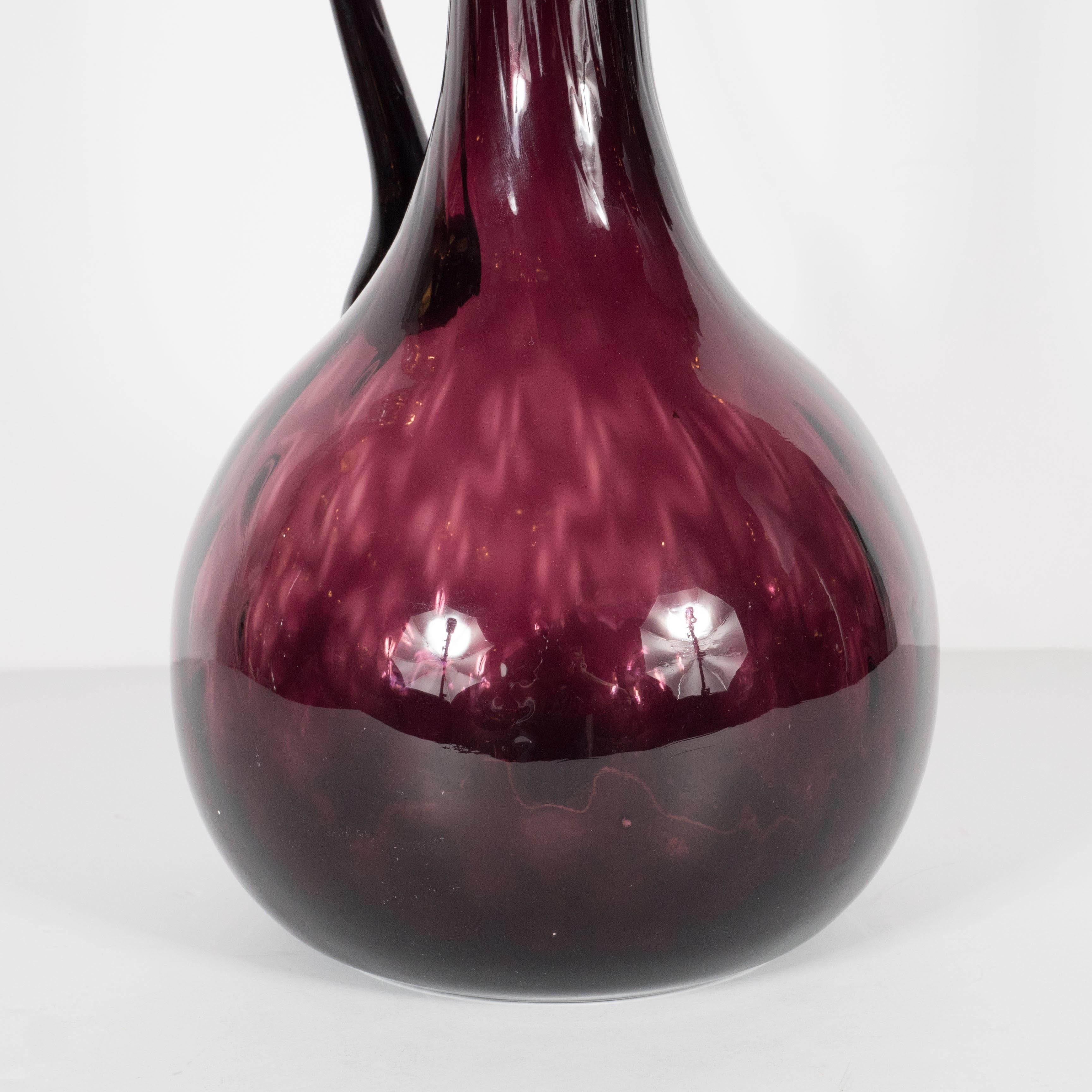 A Mid-Century modernist vase or decorative pitcher in a variation of tones of purple. A narrow neck and minimal lip is supported by a wide, bulbous vase. A gorgeous decorative object. This piece is in excellent condition.