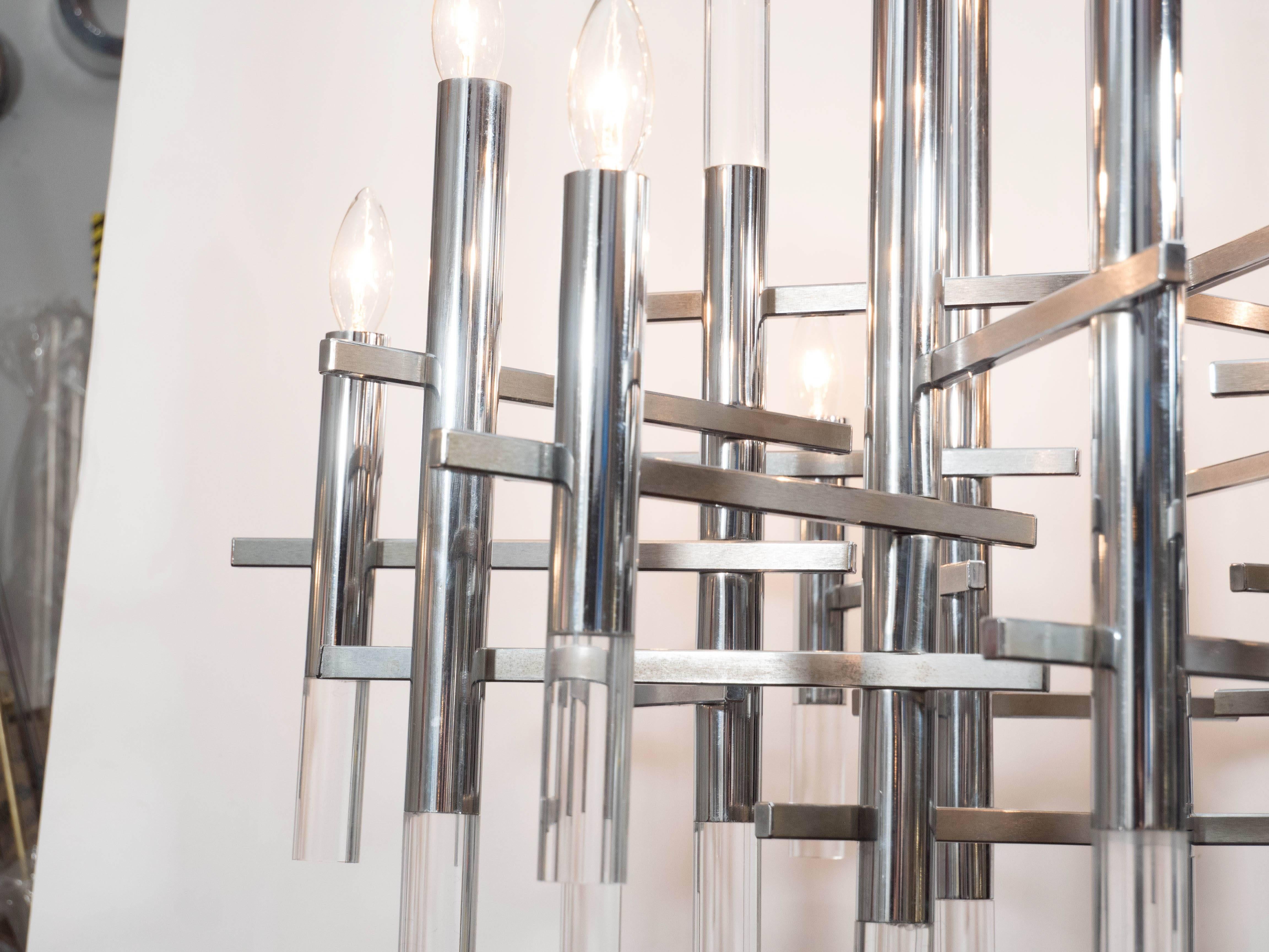 This Mid-Century Modern chrome and Lucite segment chandelier was realized in Italy by the celebrated lighting atelier Gaetano Sciolari. An abundance of polished chrome cylinders, with lucite bottoms, attach to a central chrome rod. The arms are
