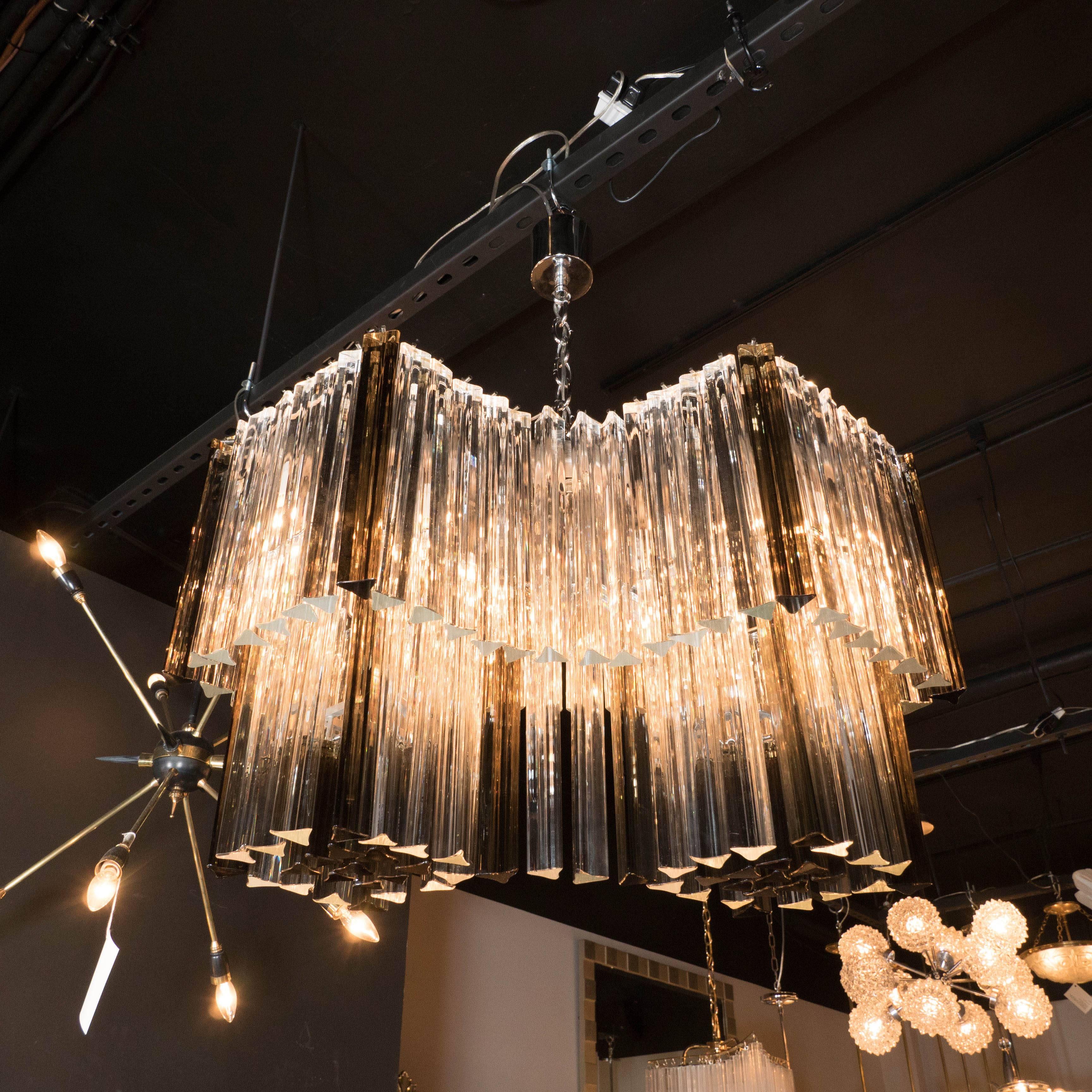 A Mid-Century infinity chandelier in smoked and clear Murano triedre prisms by Camer. Two tiers of infinity-shaped individually hung crystal successions form a waterfall effect. Gray-smoked crystals break up the clarity and add depth to the piece.