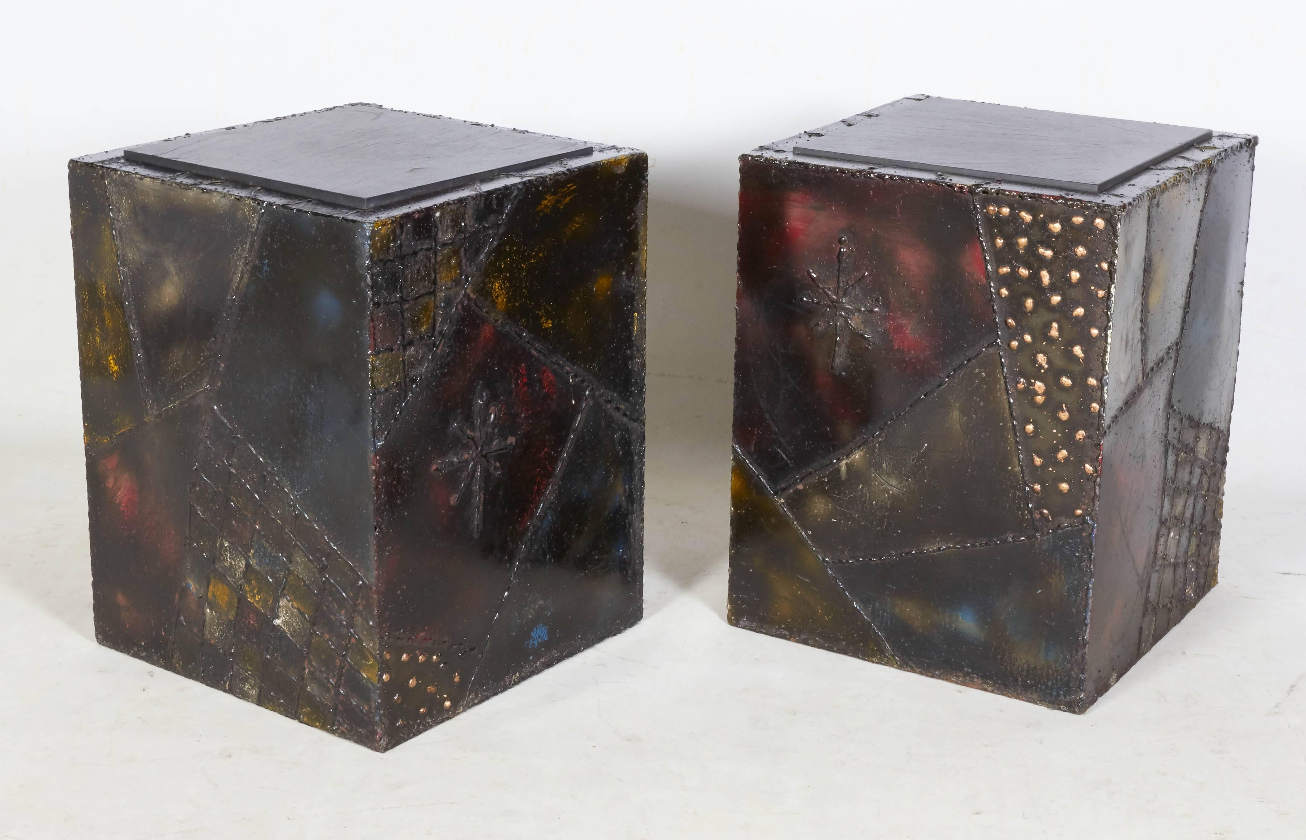 A wonderful pair of Paul Evans cube end or occasional tables with inset slate tops. The tables feature Evans trademark welding techniques along a rich, colorful steel surface. Braised brass details in the playful form of swirls, pinwheels, and