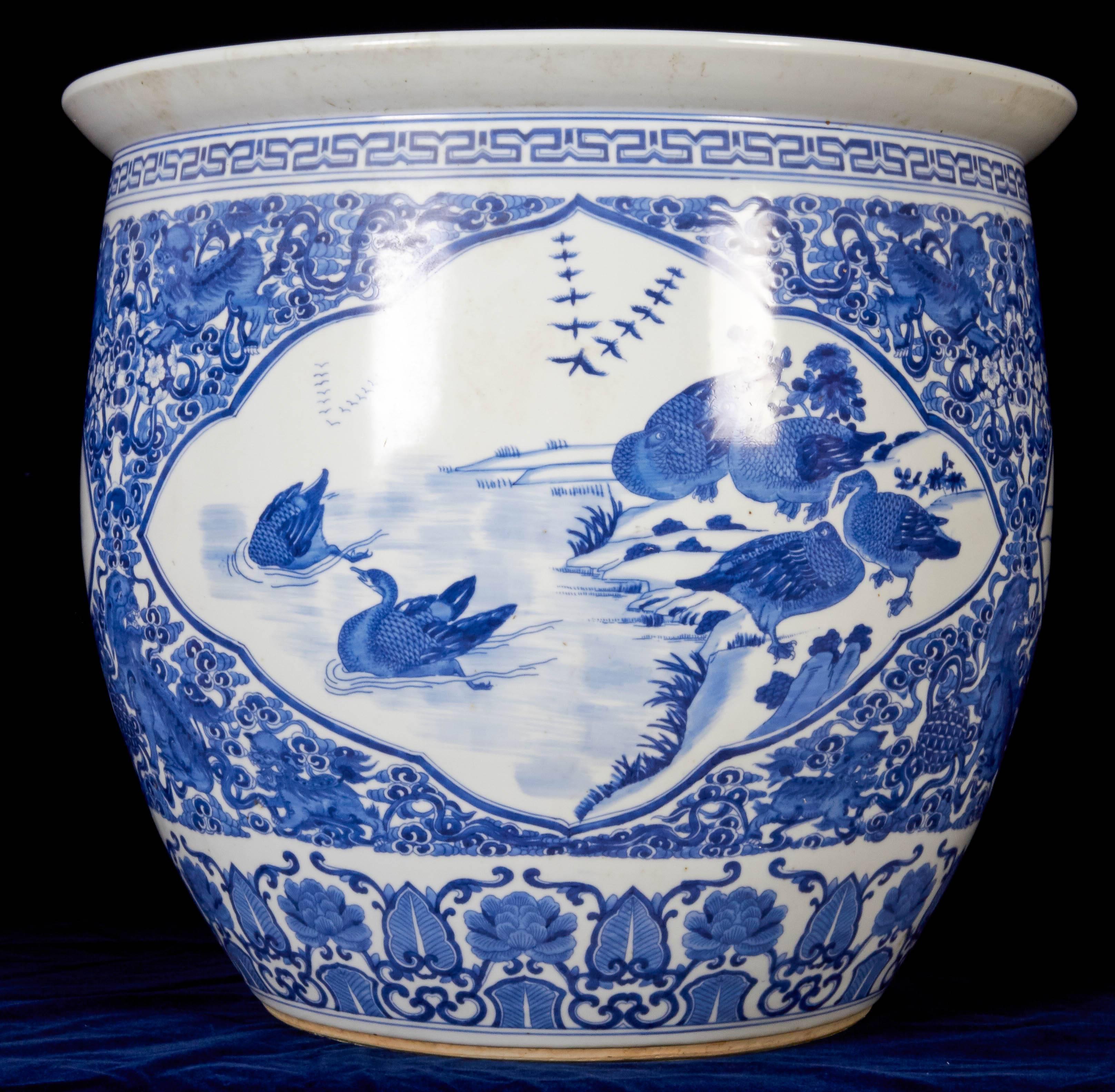 A large and quite fine pair of antique Chinese blue and white porcelain planters / fishbowls / jardinières. Each finely decorated with ducks, birds and flowers with a band of wreaths on the base below the rim.