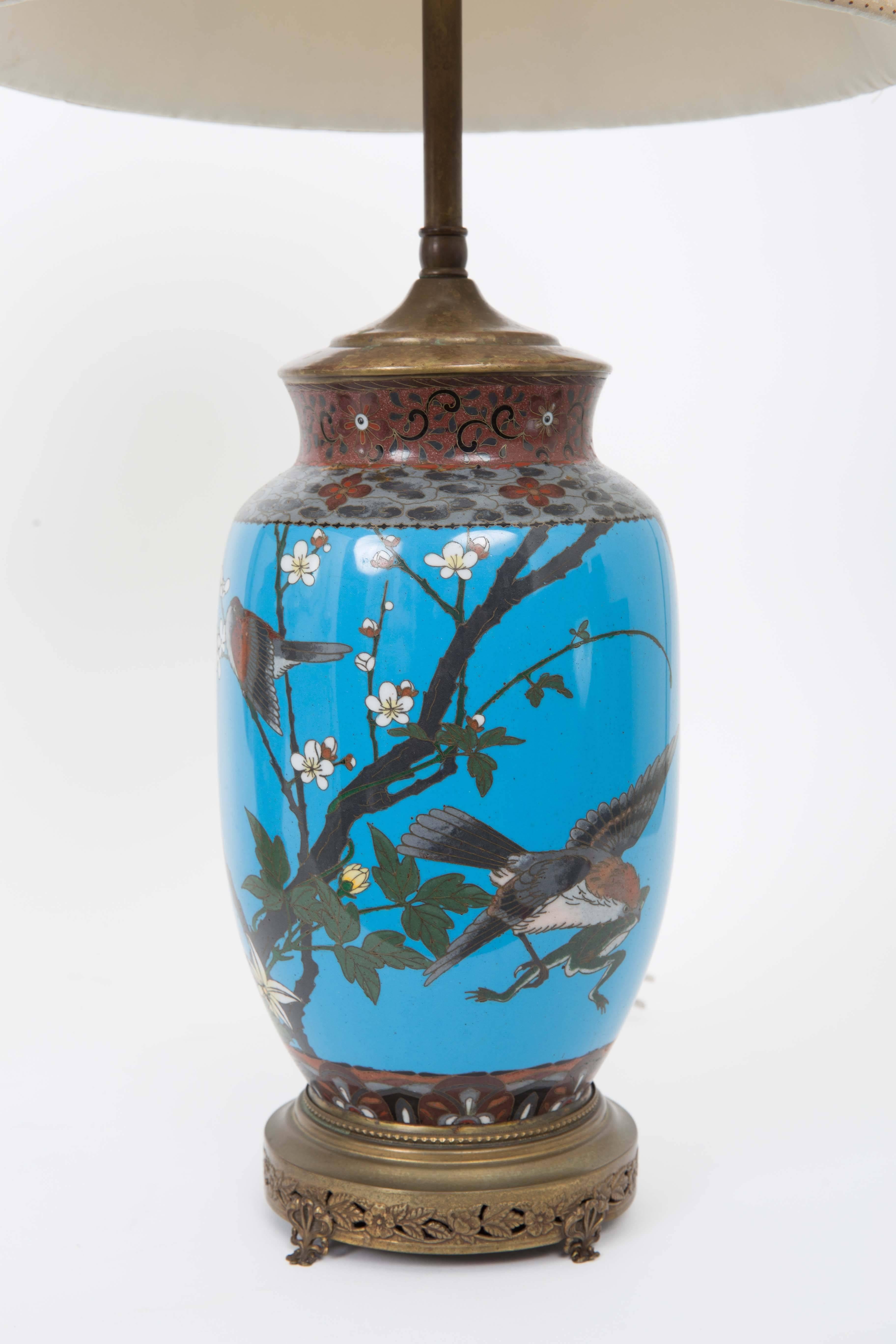 Ginger jar shape blue background with eagle and peach blossoms on one and other with song birds and cherry blossoms and branches also blue background; bordered by flowers and leaves. Brass fittings original carved stone finials.
Brass base on bow