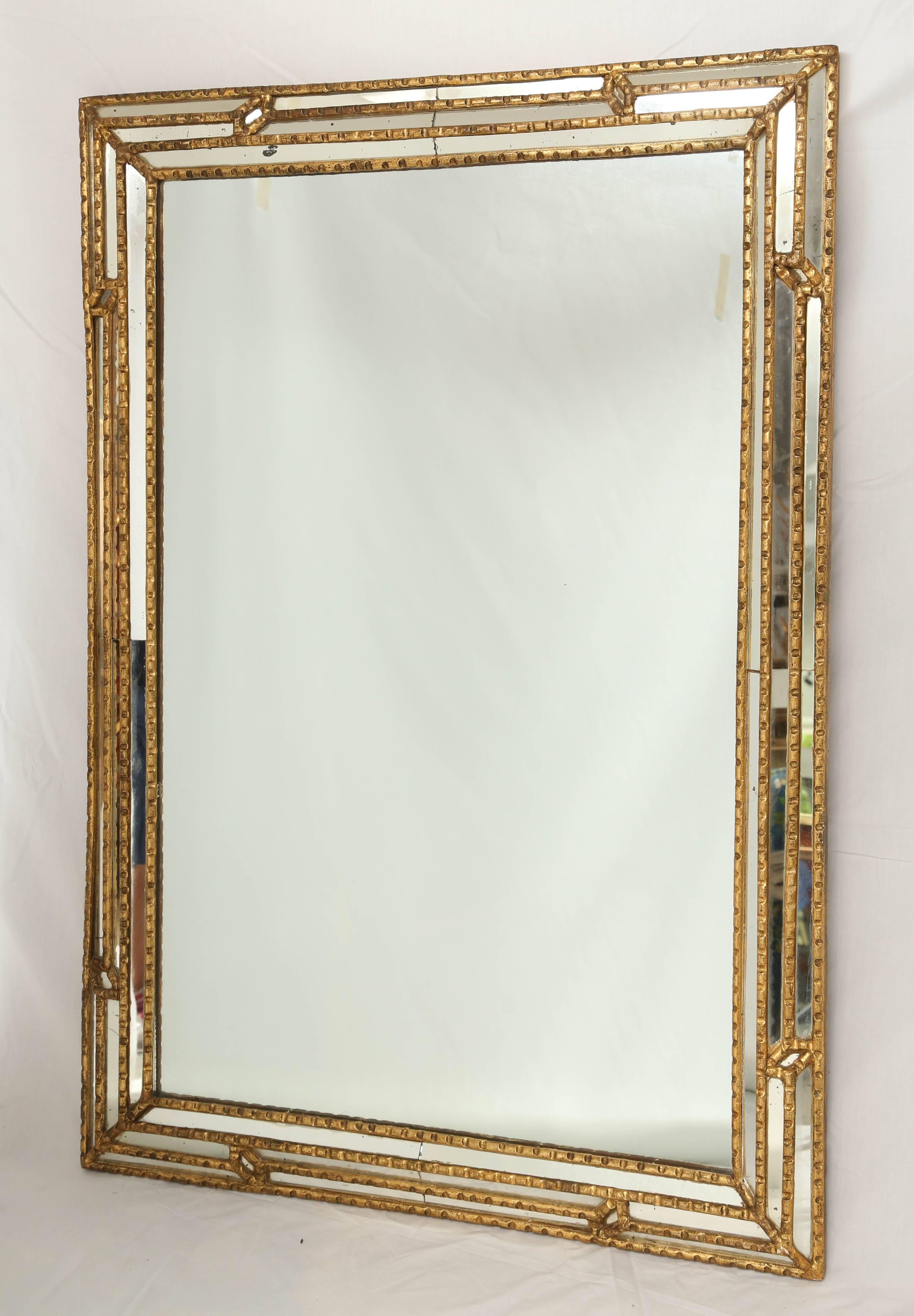 Wall mirror, having a frame of gadrooned giltwood, its rectangular mirror plate, in a mitered border of matching mirror relief.

Stock ID: D9359