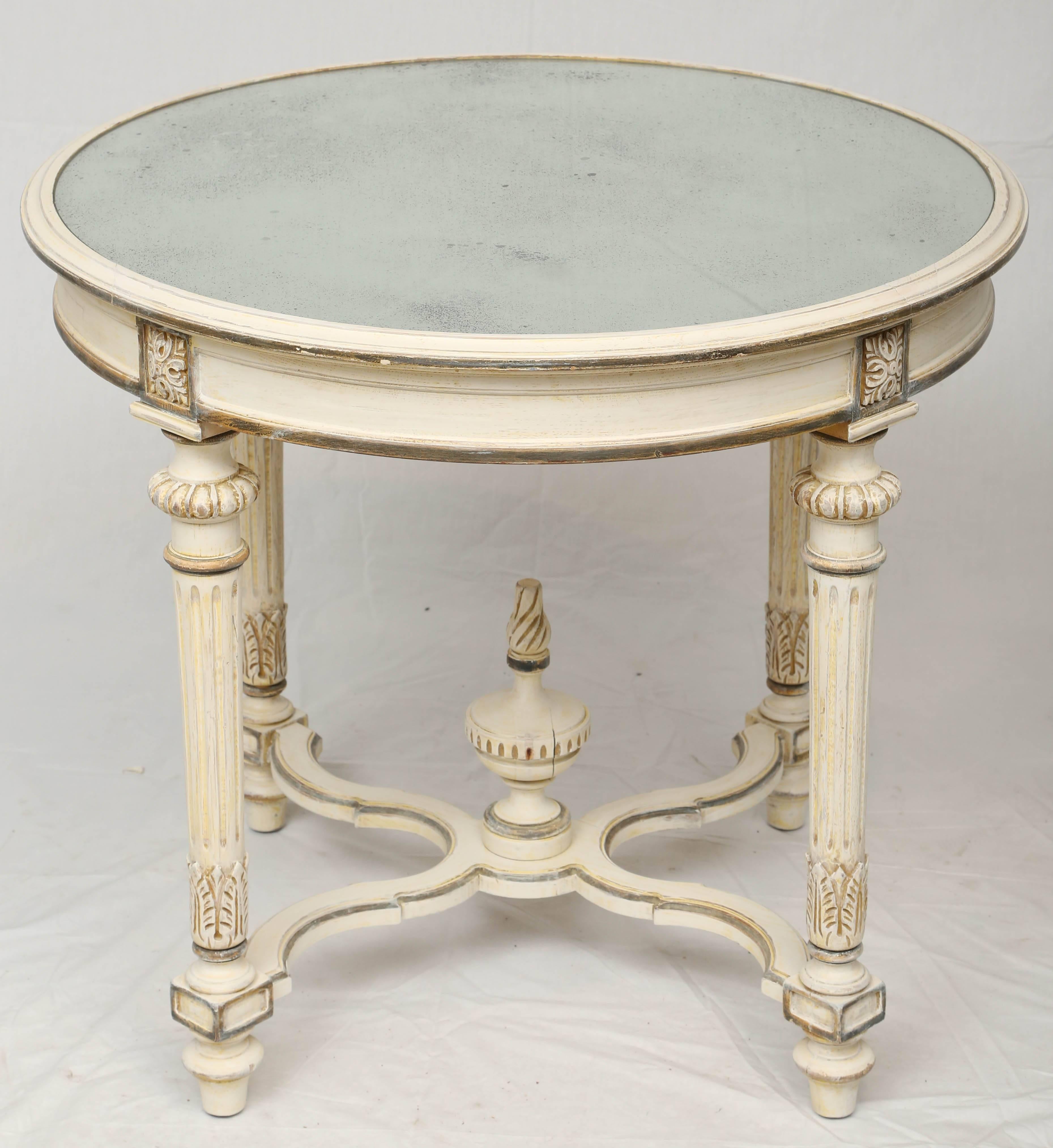 Occasional table, having a round top of distressed mirror, on painted base, channelled apron raised on rosette-headed, stop-fluted, round, tapering legs, ending in touipe feet, joined by serpentine stretcher, centered with a flaming urn finial.