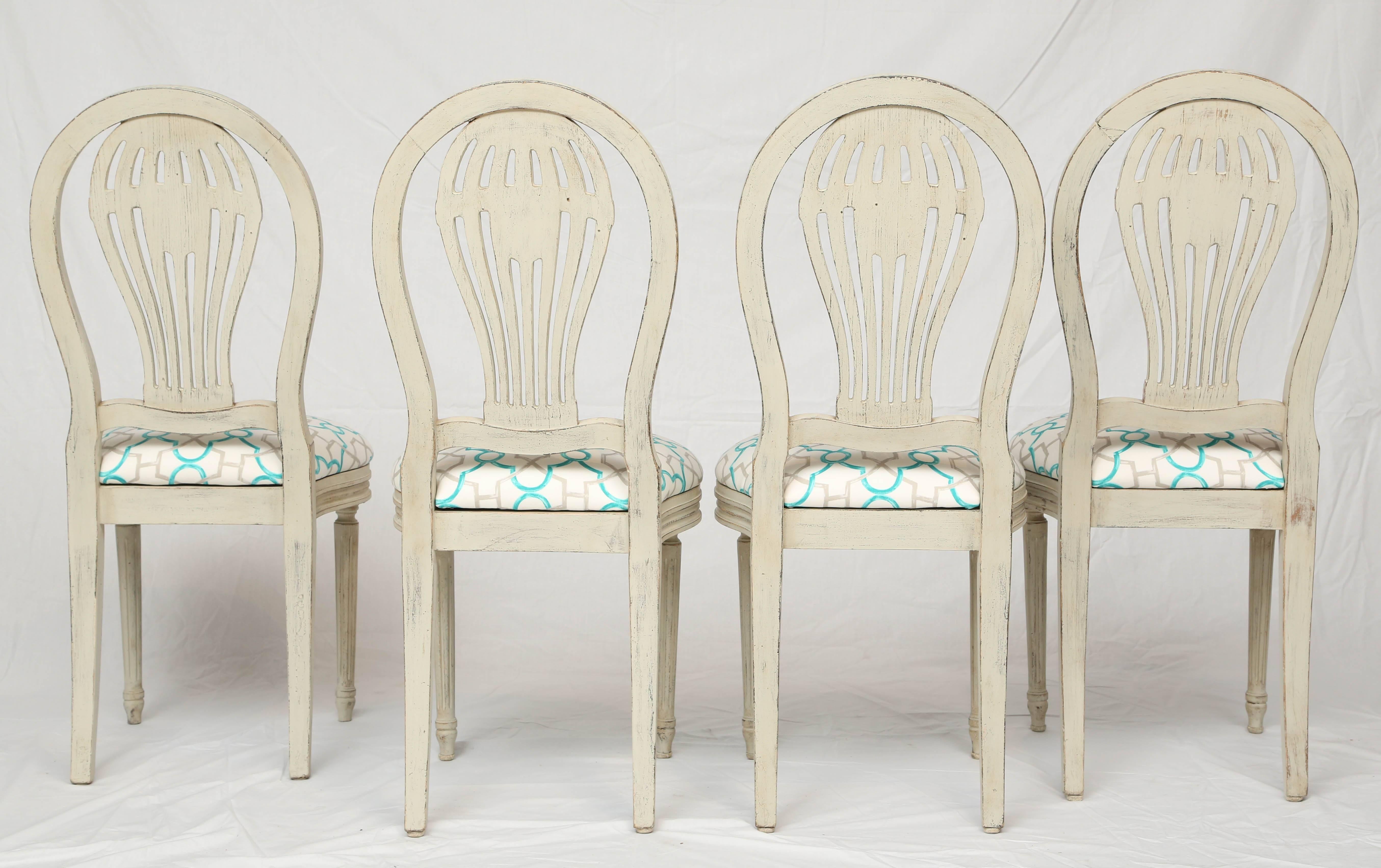 Set of four Louis XVI style side chairs, with painted and parcel silver gilt channeled frame, each arched back centered with a pierced and carved hot air balloon backs plat, on drop-in seat, on bowed rail, raised on rosette-headed, round, tapering,