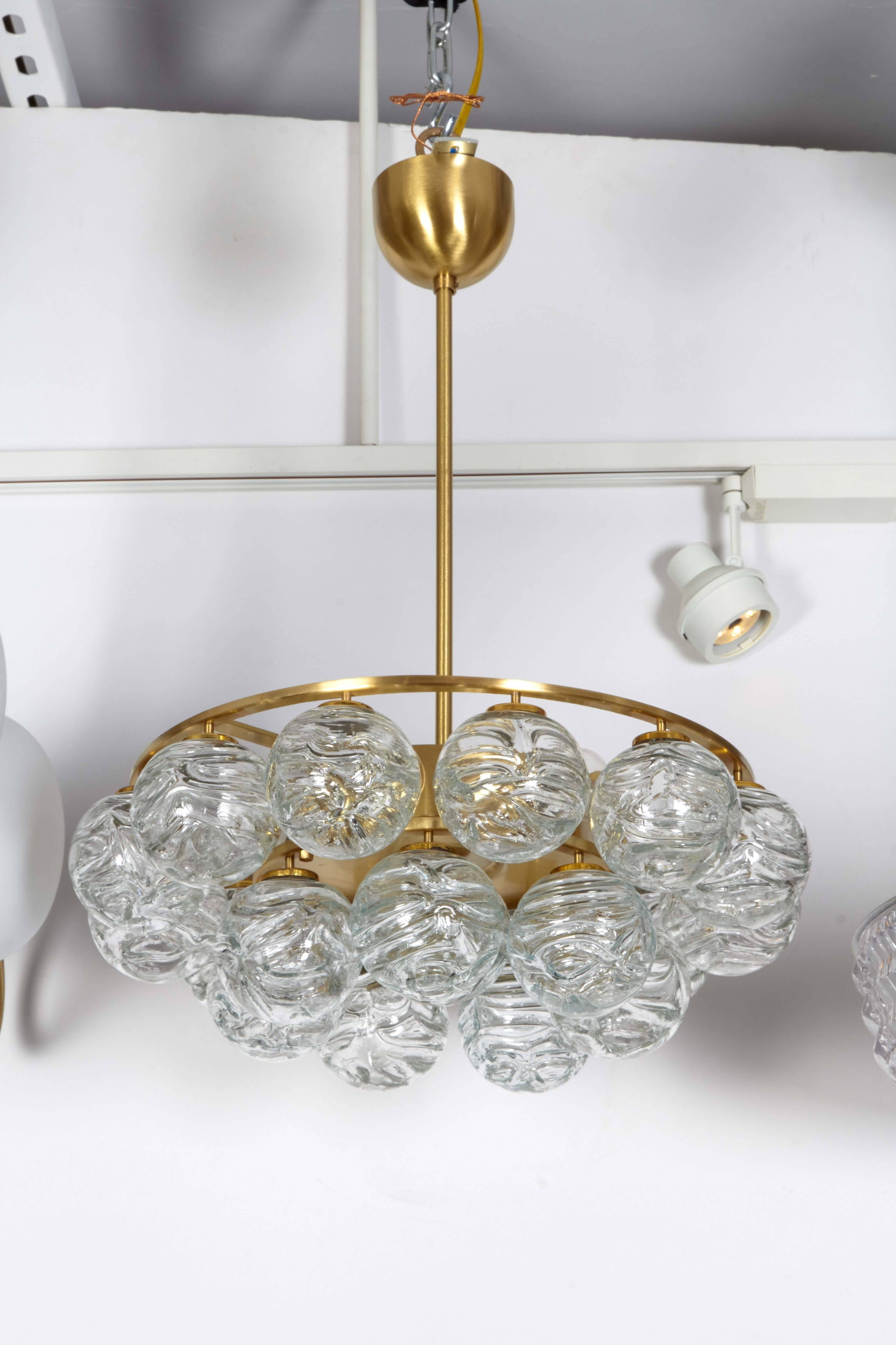 Striking Mid-Century pendant chandelier with two rows of suspended ice glass spheres and one in center, all on a satin brass frame. Uses six chandelier type bulbs, 40W max each. Rewired for use in the USA.