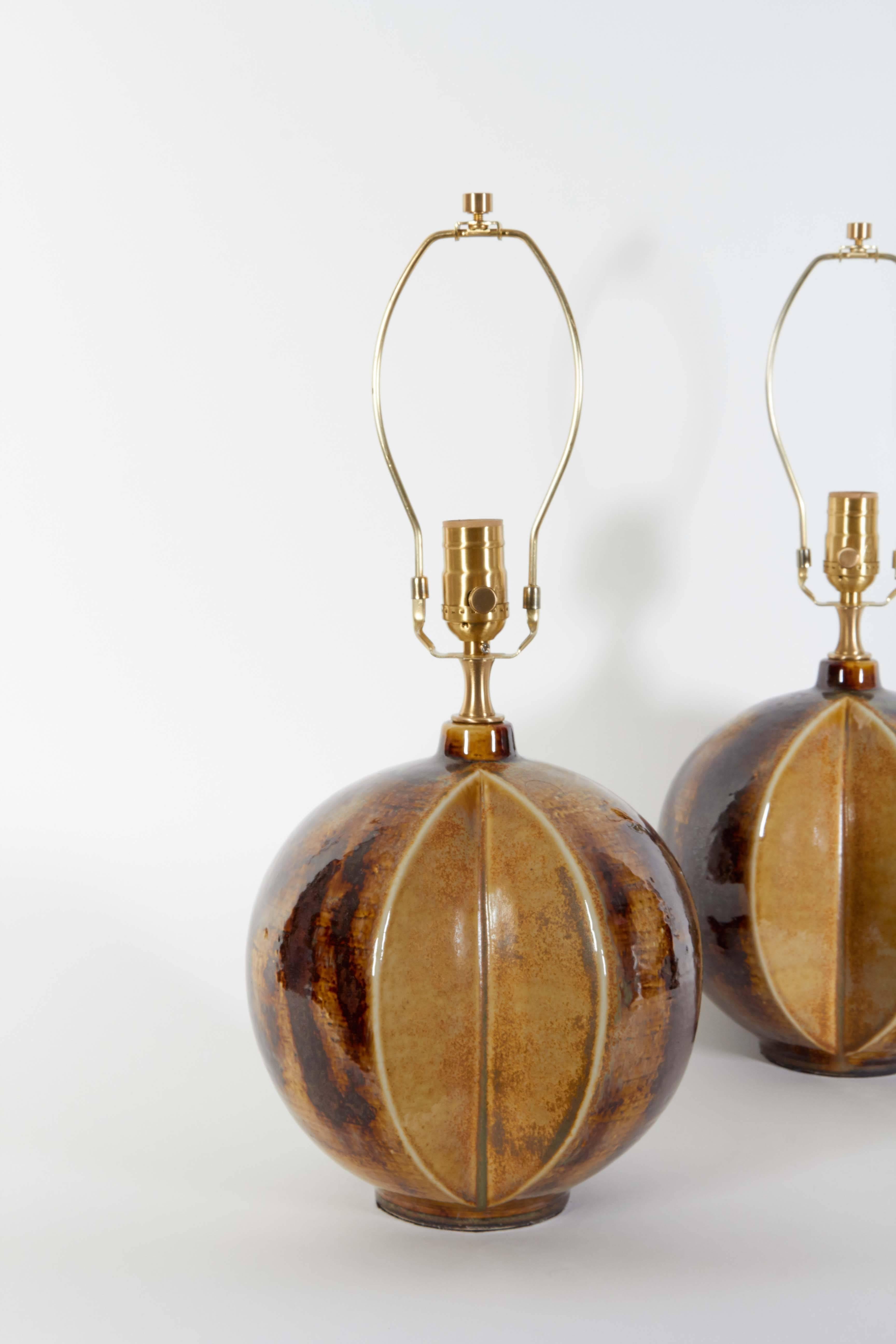 Unusual pair of Danish modern ceramic lamps with an abstract sectioned melon form and terrific brown and tan glaze. Retrofitted with satin brass hardware and new wiring for use in the USA.