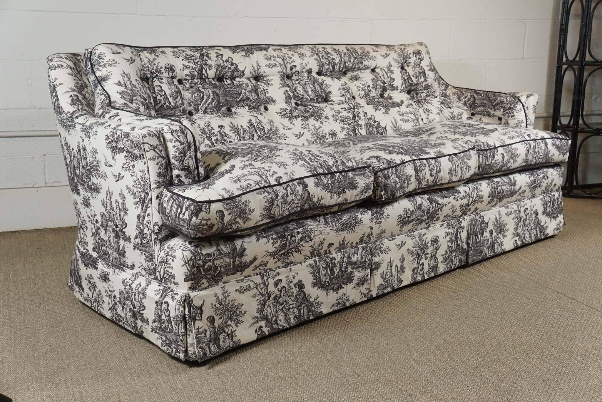 Here is a beautiful custom-made sofa in a black and white toile fabric. The attached back is tufted and the loose seat cushions are down. There is black cording on all the cushions. The sofa is gently used but in great condition.