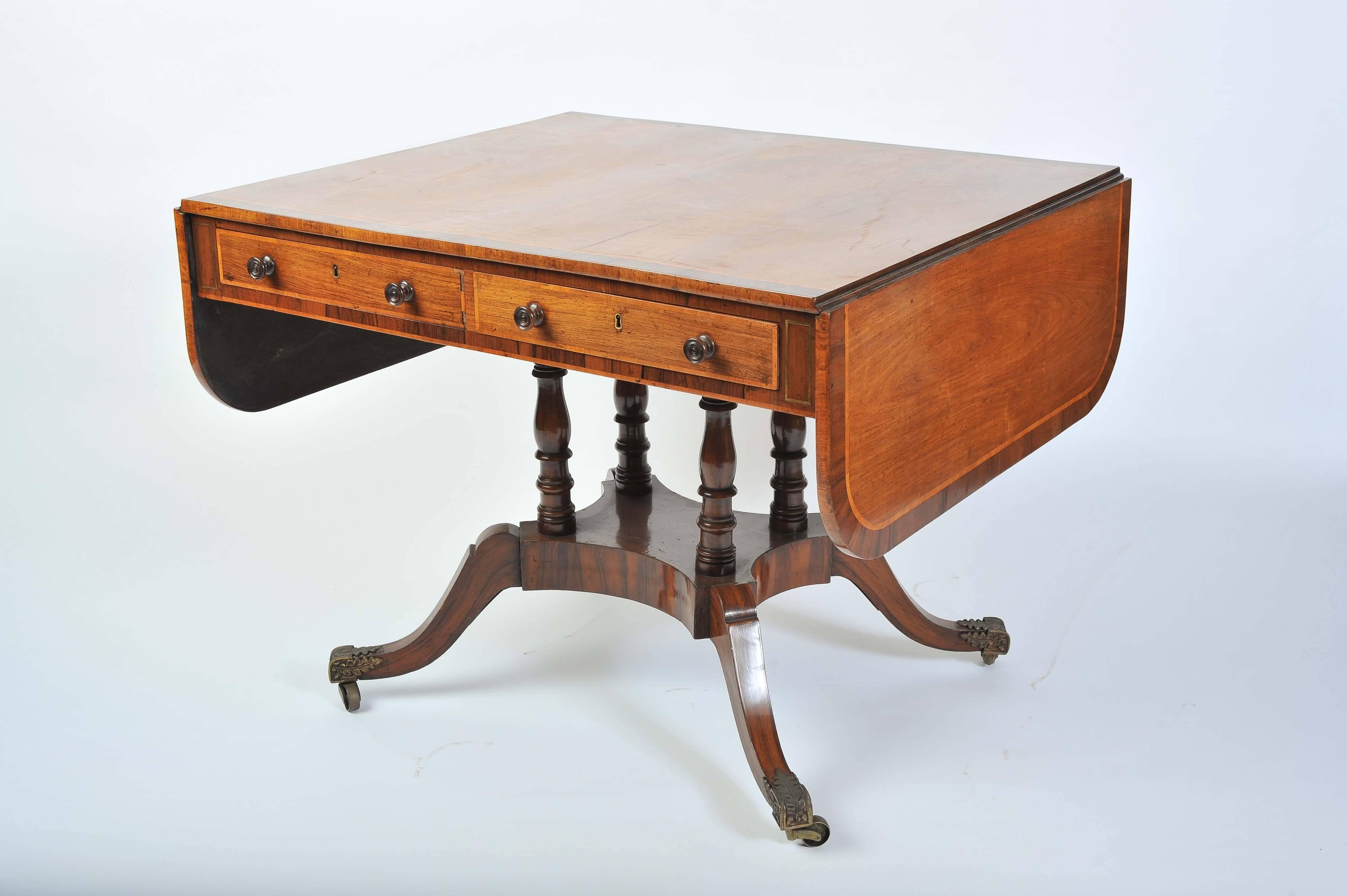 A rare and good quality pair of Regency period rosewood sofa tables. Having rosewood crossbanding, boxwood stringing and brass inlay. Two mahogany lined drawers to one side, dummy drawers to the reverse. Raised on ring turn supports, a platform and