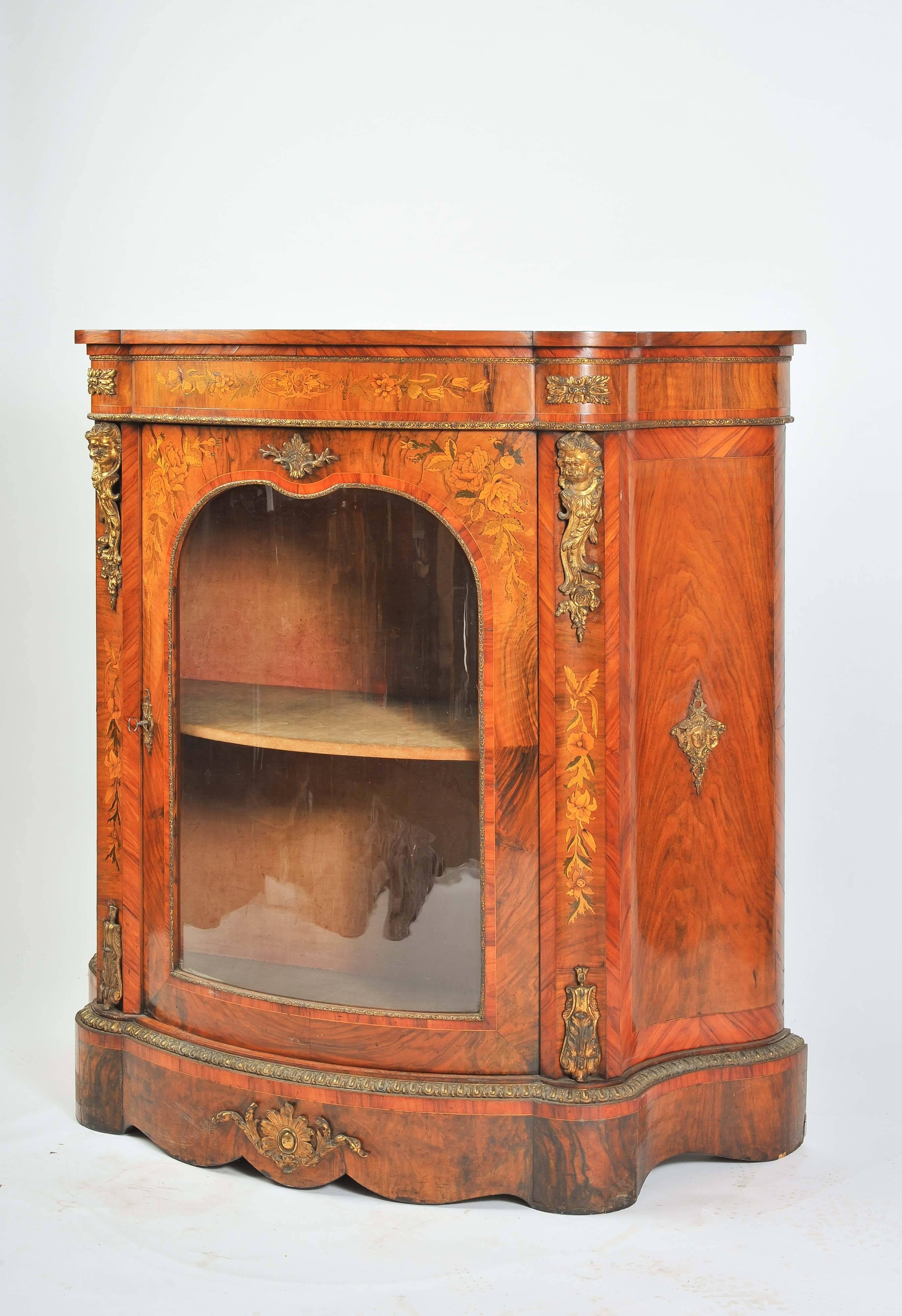 A good quality Victorian figured walnut marquetry inlaid side cabinet. Having a bowed glazed single door, opening to reveal a single shelf. Tulipwood banding, boxwood marquetry inlay and ormolu mounts depicting cherubs and foliage. Raised on a