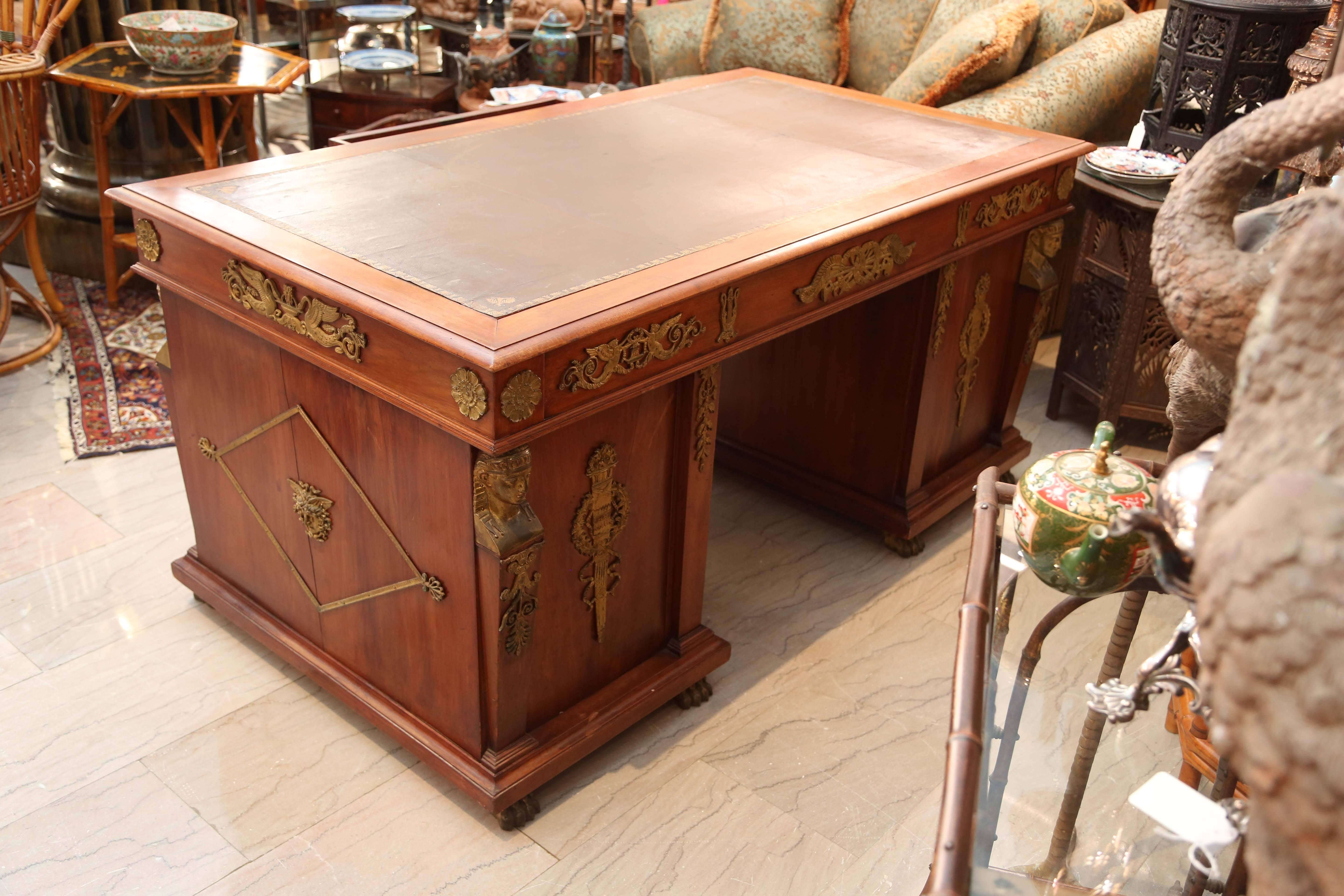 Napoleonic Egyptian revival desk. The epitome of strong Empire style, profusely embellished with exquisitely fine ormolu mounts on all four sides and the leather top is original.