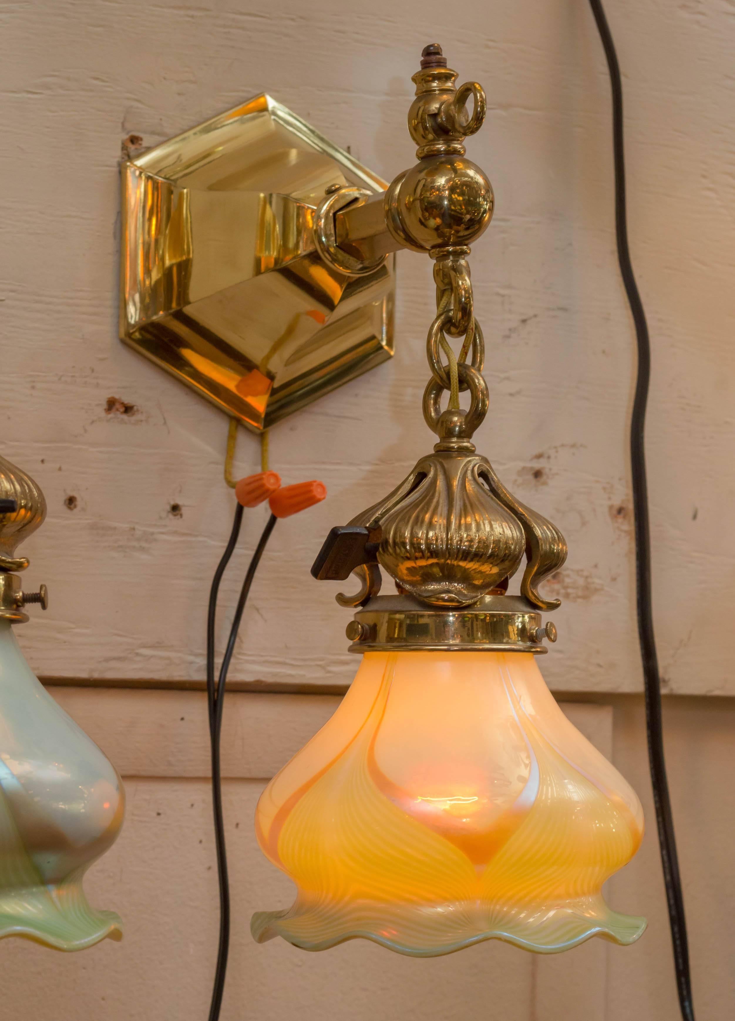 These polished brass sconces were originally gas and electric. If you look at the upper portion above the arm, you will see where a gas flame was originally used. It is all electrified now. The handblown art glass shades are exceptional. The pulled