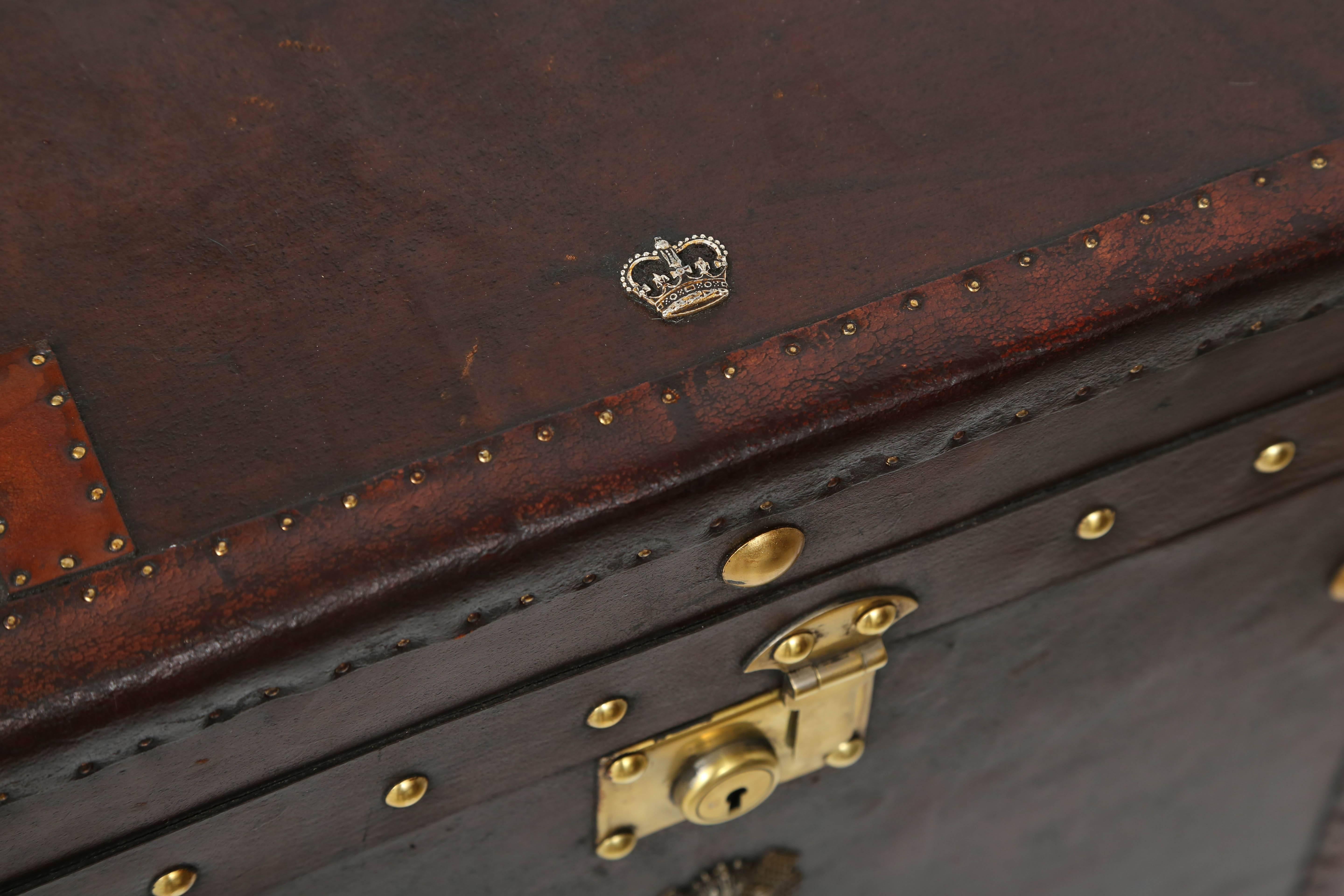 This handsome pair of leather-bound storage trunks were recently purchased in London and have been professionally restored. The leather is a dark brown and the hardware a warm-colored brass. There are armorial-type mounts in a silver-toned metal