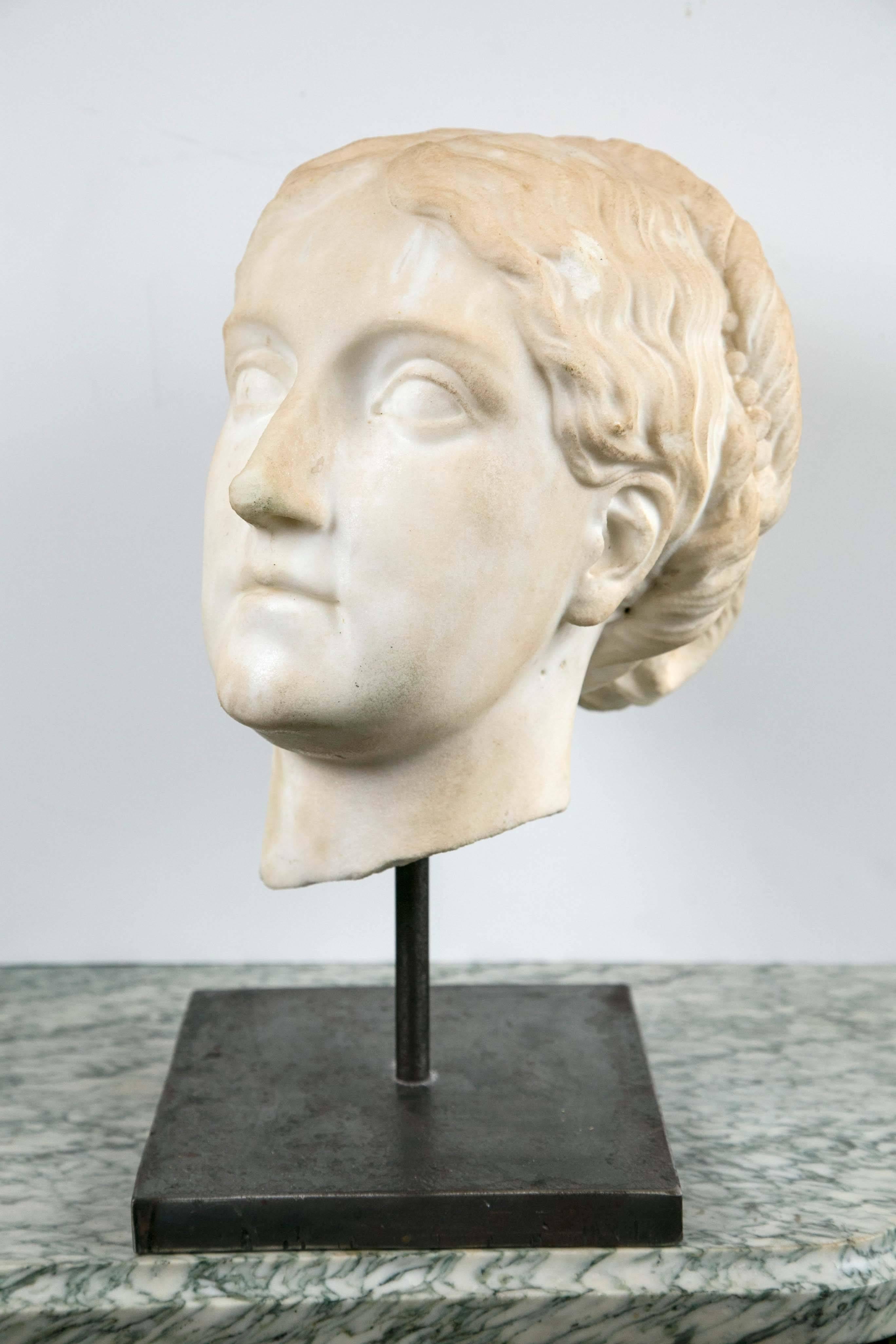 Set on a removable custom polished steel base, a classical style white marble bust of a woman.