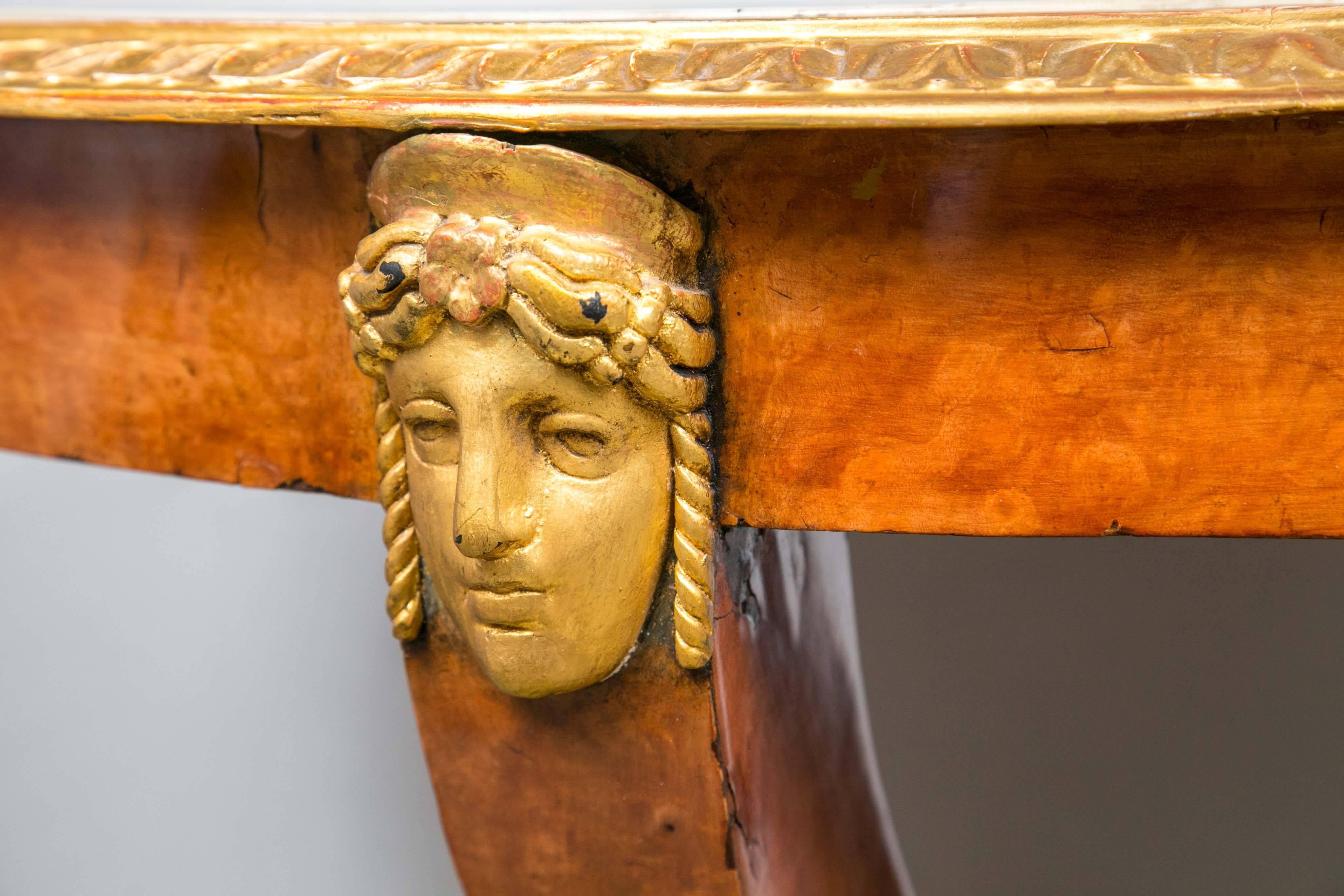 This center table has a marble top that sits within a gilt wood gadrooned rim. The marble is painted with a center of Cupid receiving a laurel wreath from Psyche. It is surrounded by paintings of a frolicking cupid within gilded framing, separated