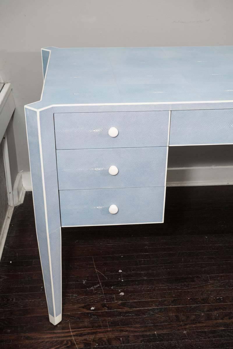 Custom made-to-order blue shagreen desk with bone trim. Customization of dimensions and colors is available. The piece shown is in a custom blue color (no longer available) with a pre-finished maple veneer in the back and inside of drawers. The back