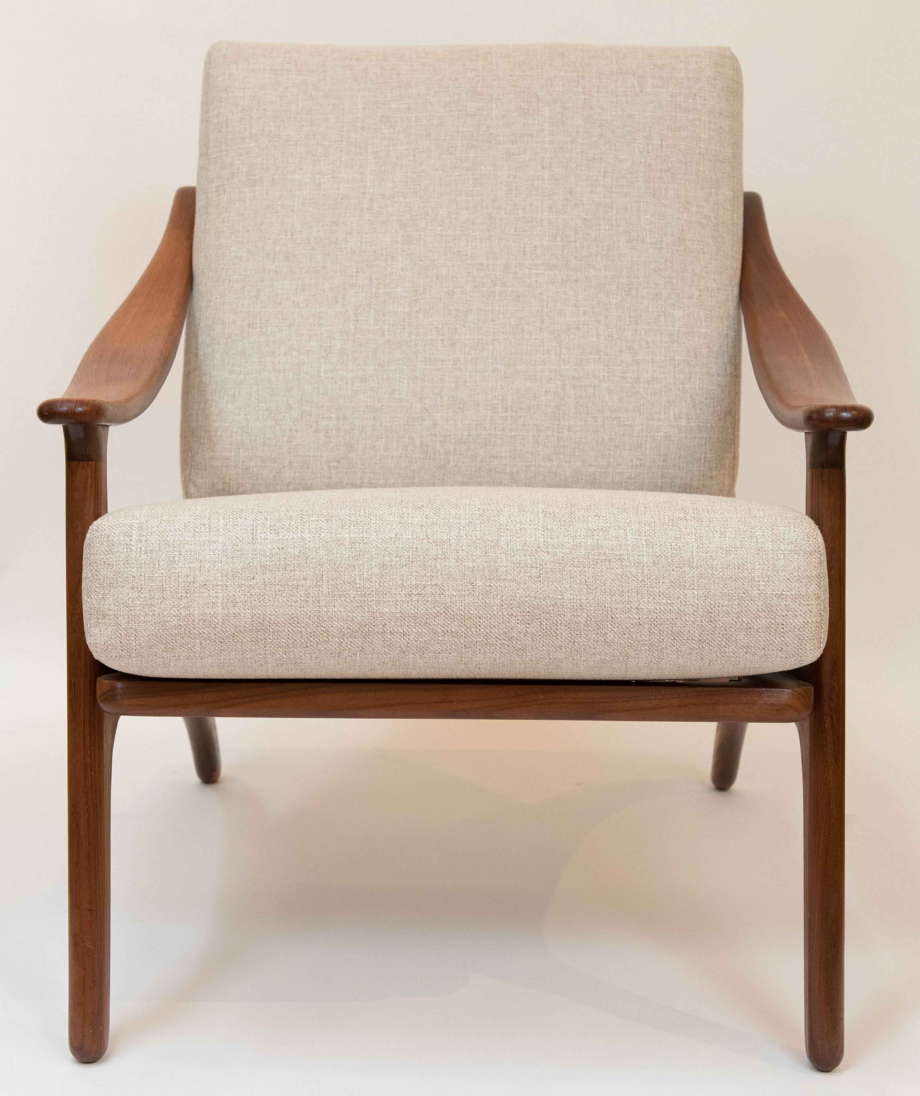 A pair of elegant teak arm chairs with rich wood grain and lean lines. This savy
pair of Danish chairs have been reupholstered in a warm soft oatmeal
colored fabric with new foam interiors.