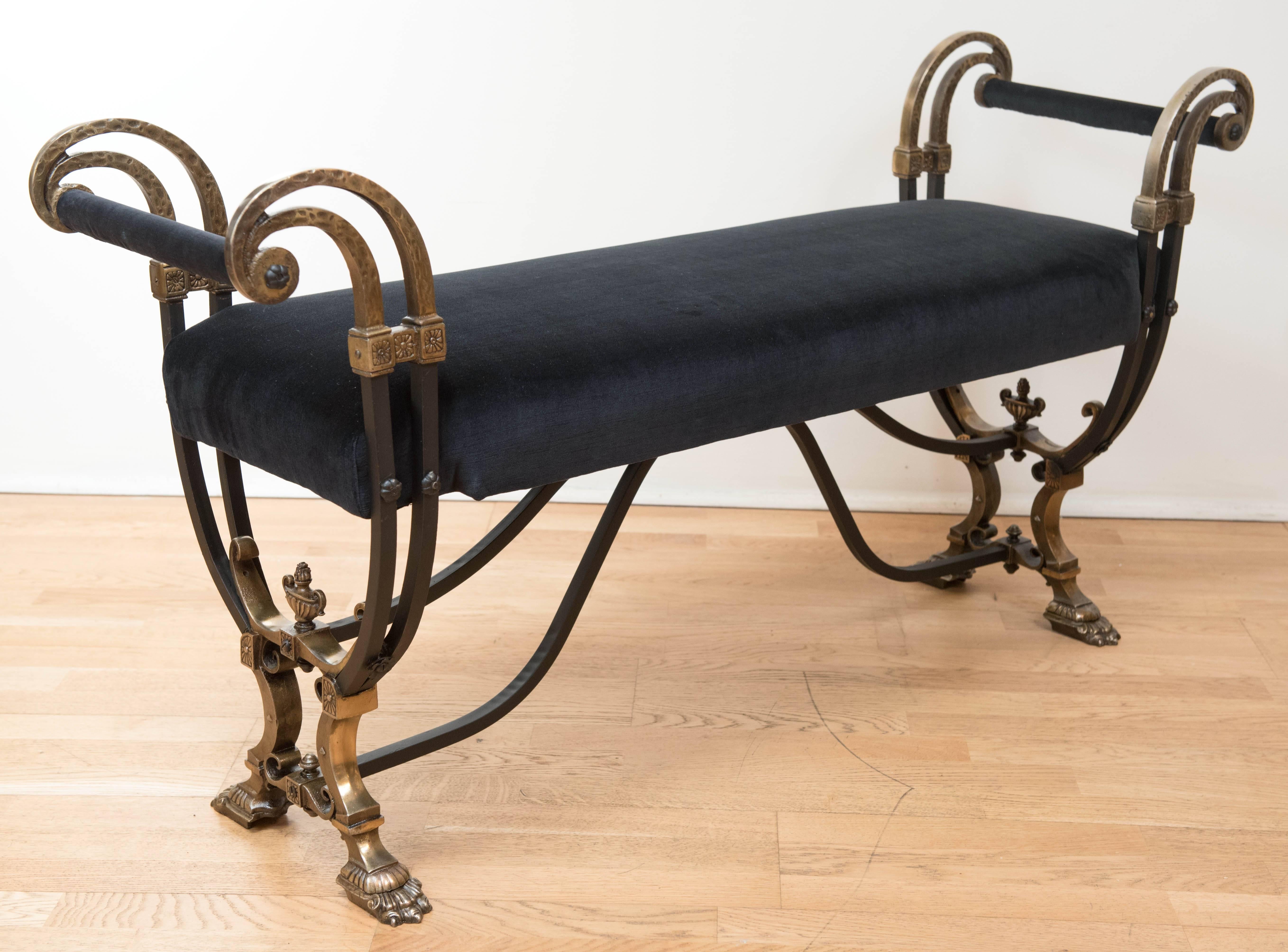 A most magnificent and detailed hallway bench in painted wrought iron with solid cast metal details in brass plate. The bench and handles have been reupholstered in black velvet.